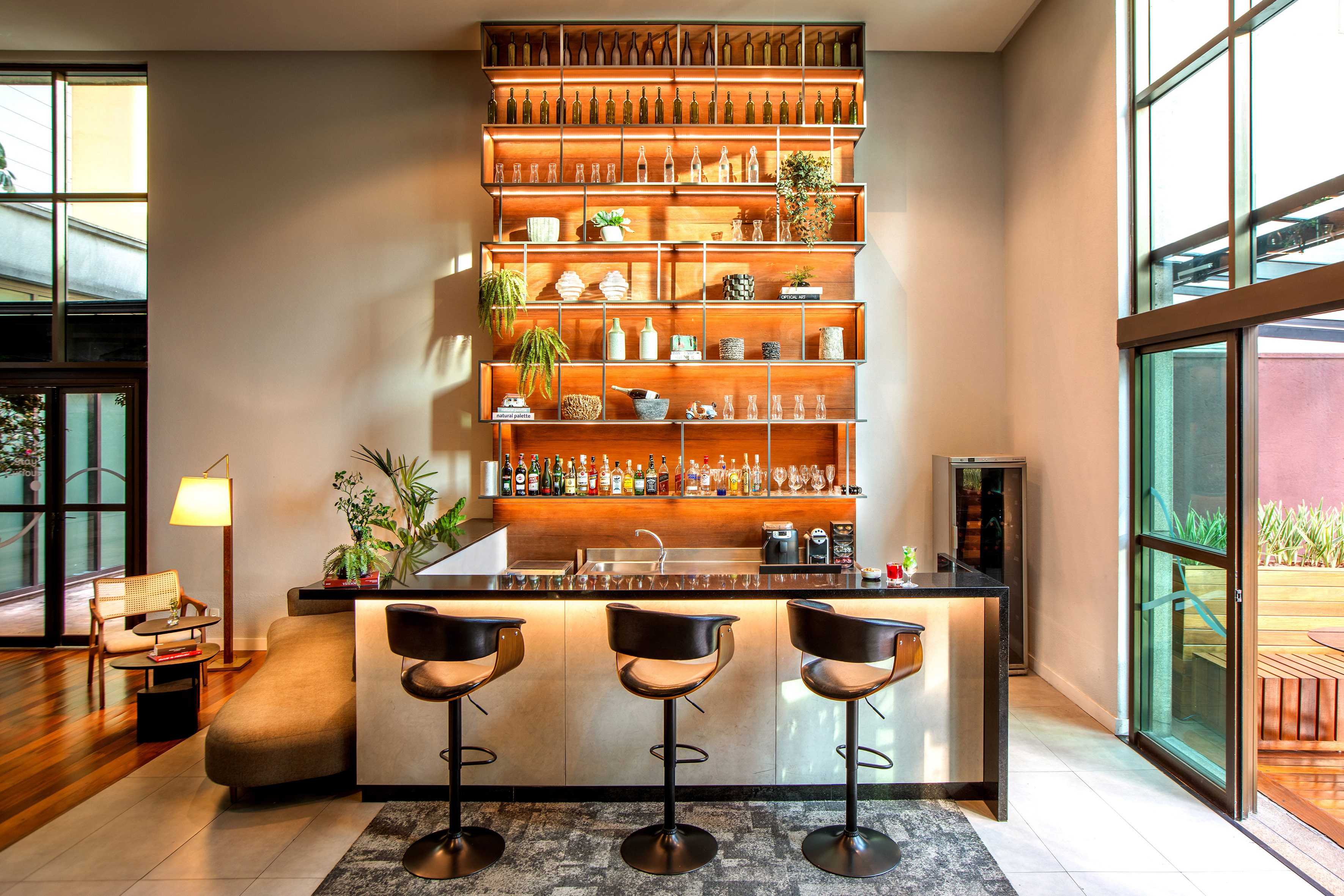 Modern bar lounge with backlit liquor display and bar stools.