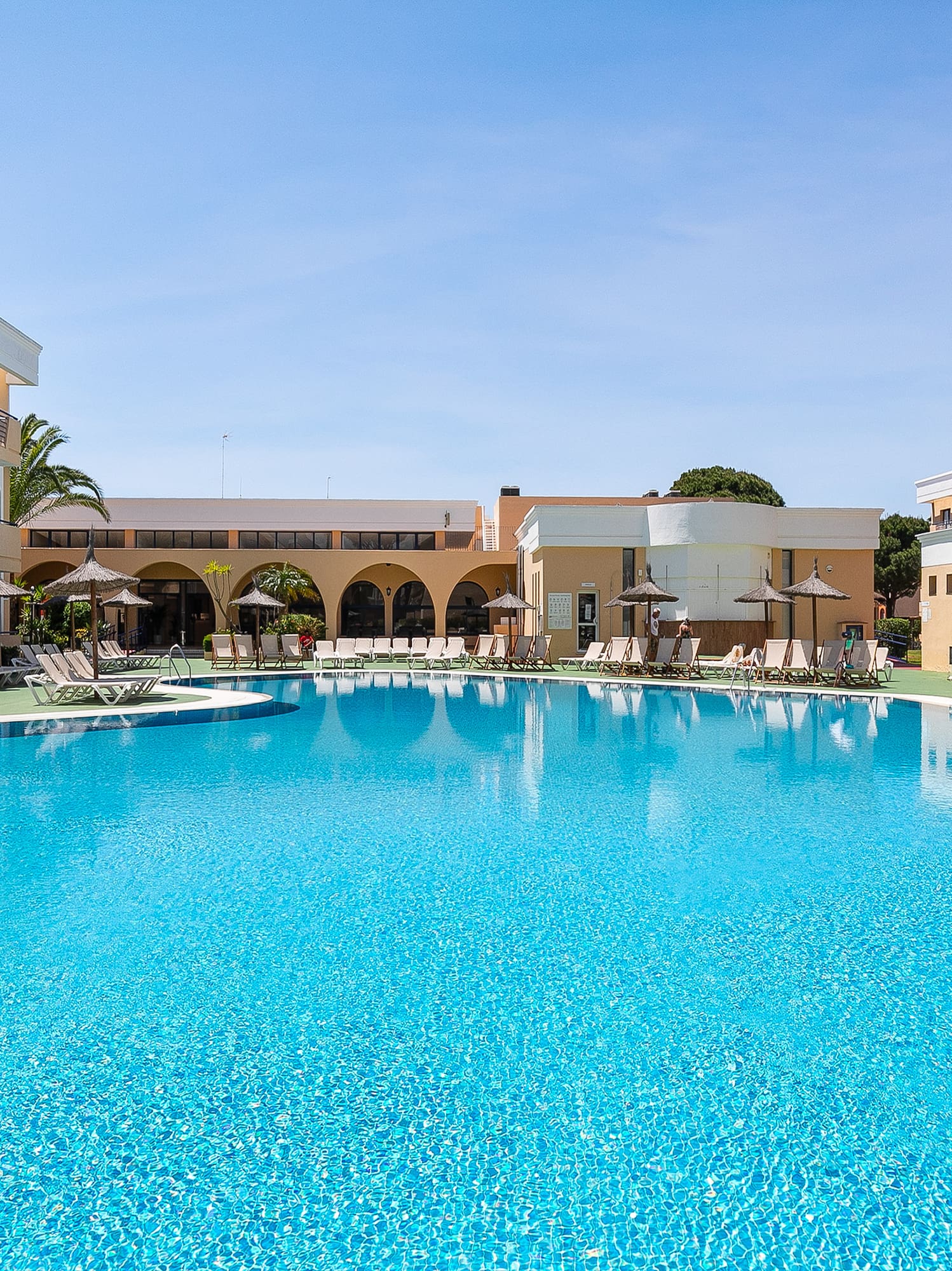 a swimming pool with a building and umbrellas