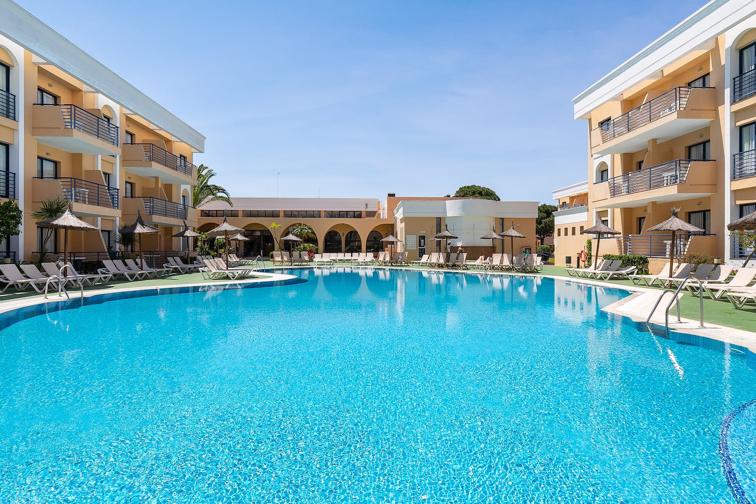 a swimming pool with a building and umbrellas