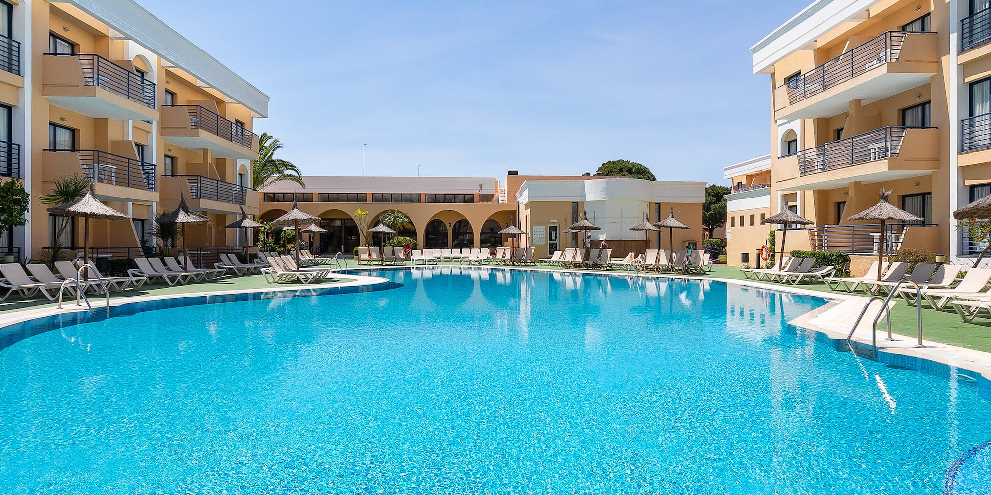 a swimming pool with a building and umbrellas