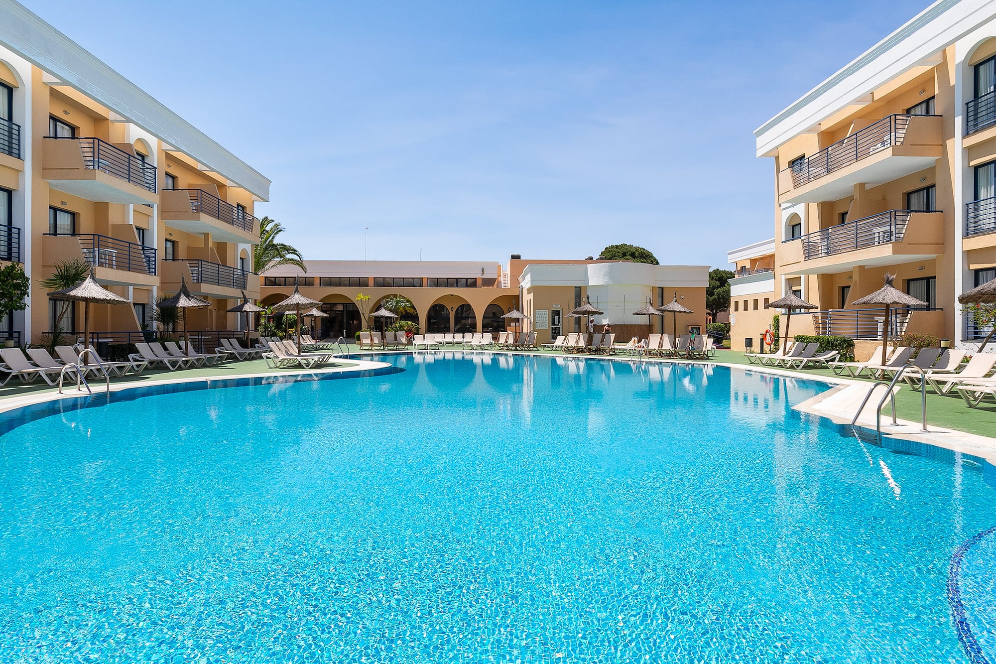 a swimming pool with a building and umbrellas