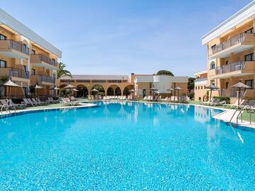a swimming pool with a building and umbrellas