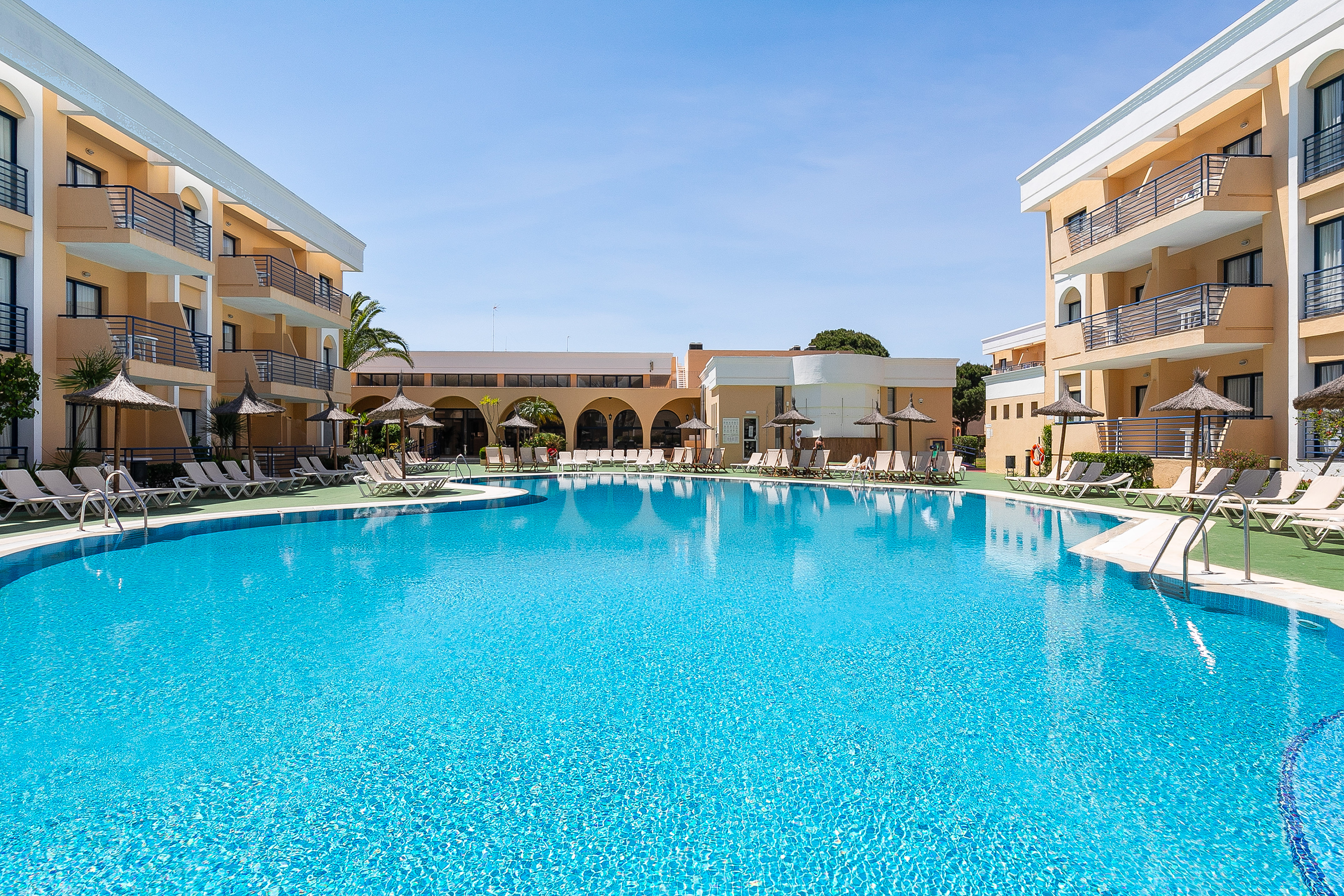 a swimming pool with a building and umbrellas