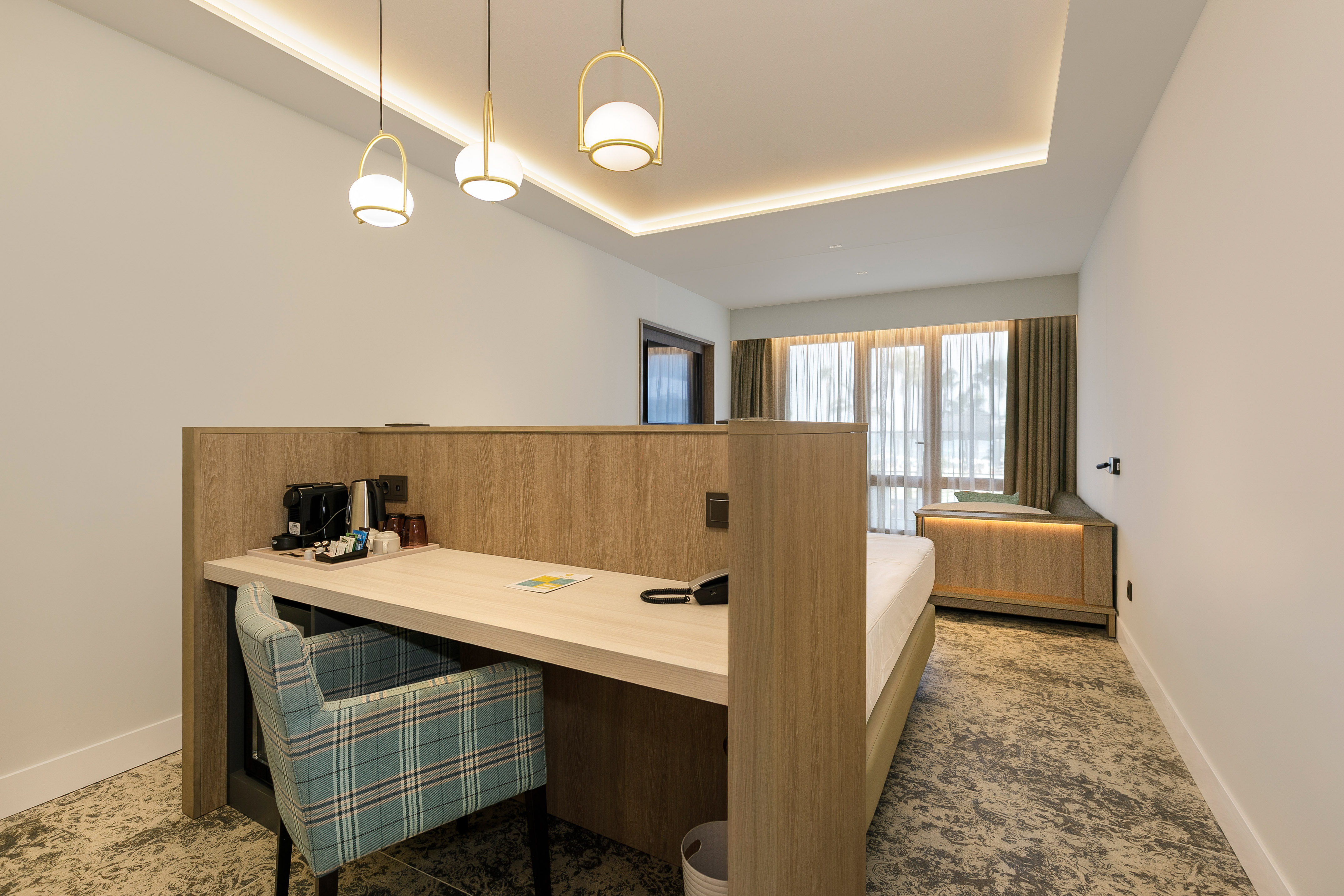Contemporary hotel room interior with work desk, bed, and accent lighting.