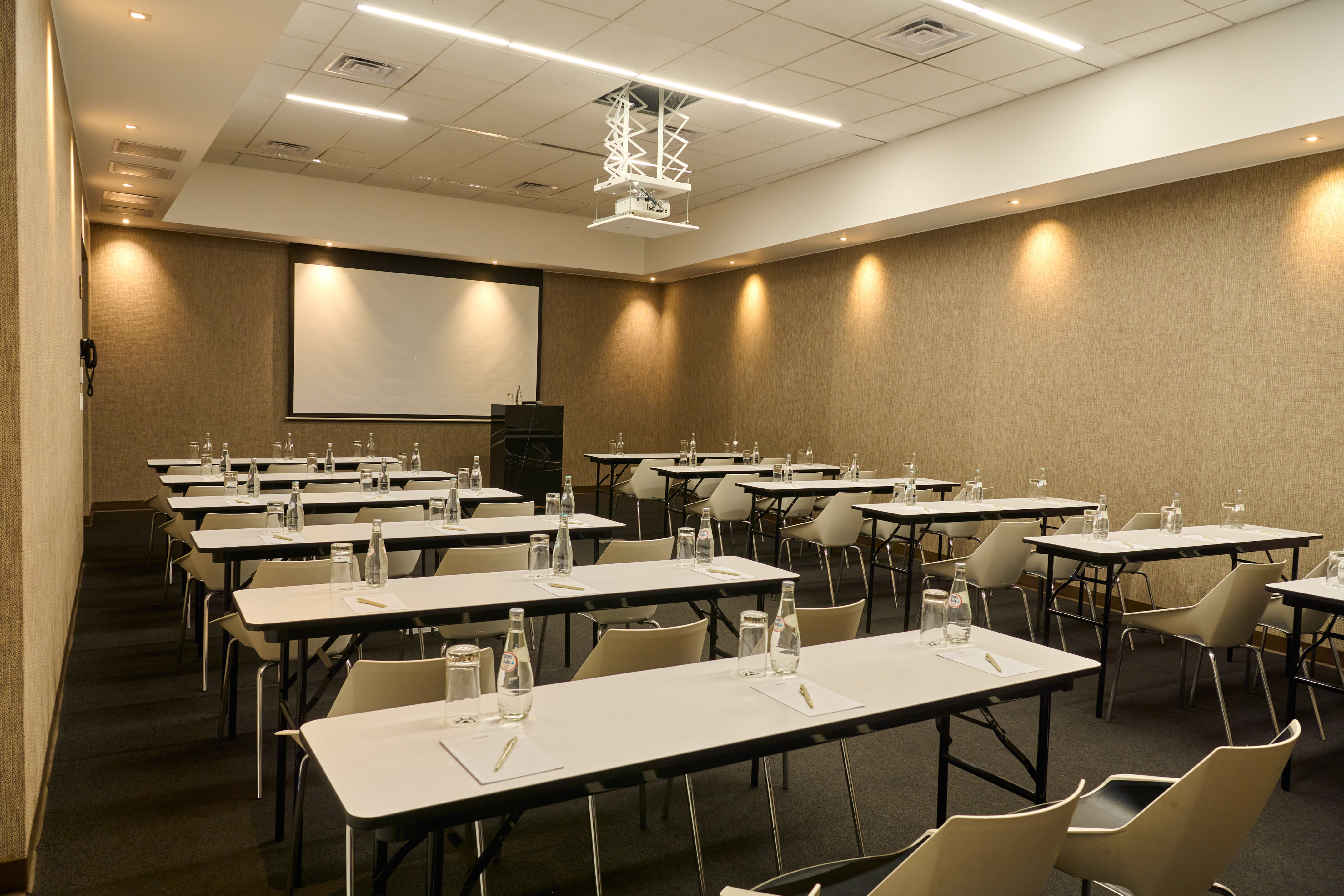 Conference room with classroom setup, projection screen, and projector.