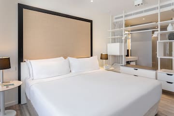 a bed with white sheets and a brown headboard
