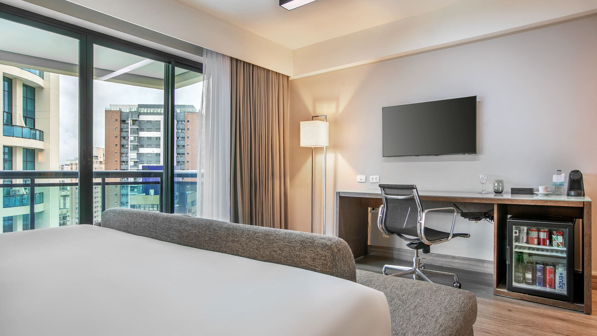 Quarto de hotel moderno com cama, mesa de trabalho e vista para a cidade. - Deluxe Queen Room com Varanda - Meliá Ibirapuera, São Paulo