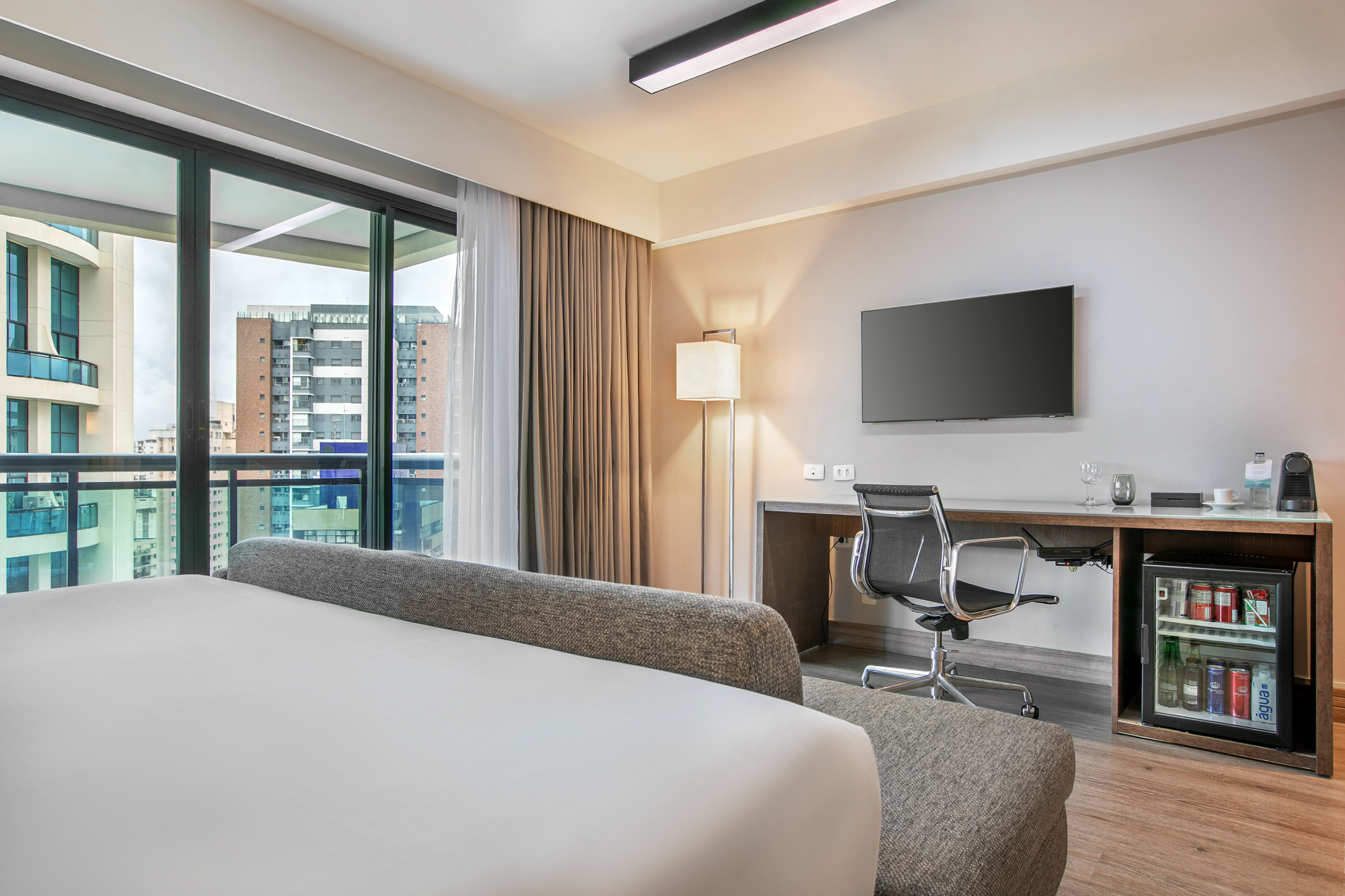 Quarto de hotel moderno com cama, mesa de trabalho e vista para a cidade. - Deluxe Queen Room com Varanda - Meliá Ibirapuera, São Paulo