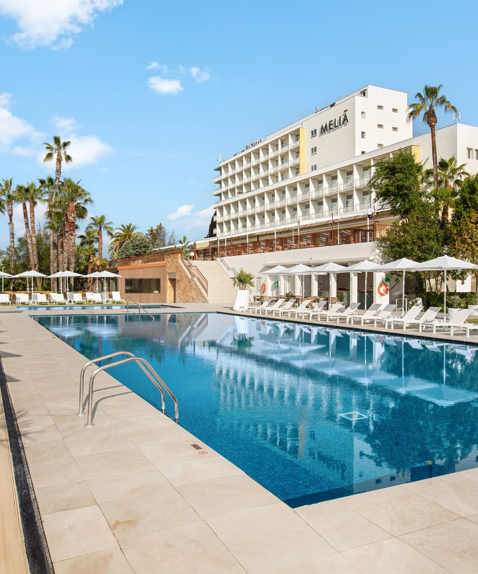 a pool with chairs and umbrellas in front of a building