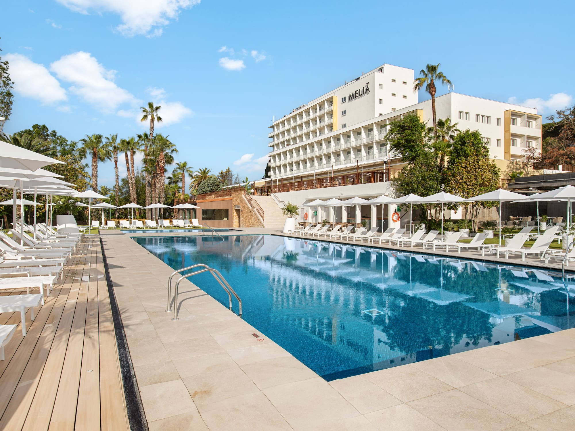 a pool with chairs and umbrellas in front of a building