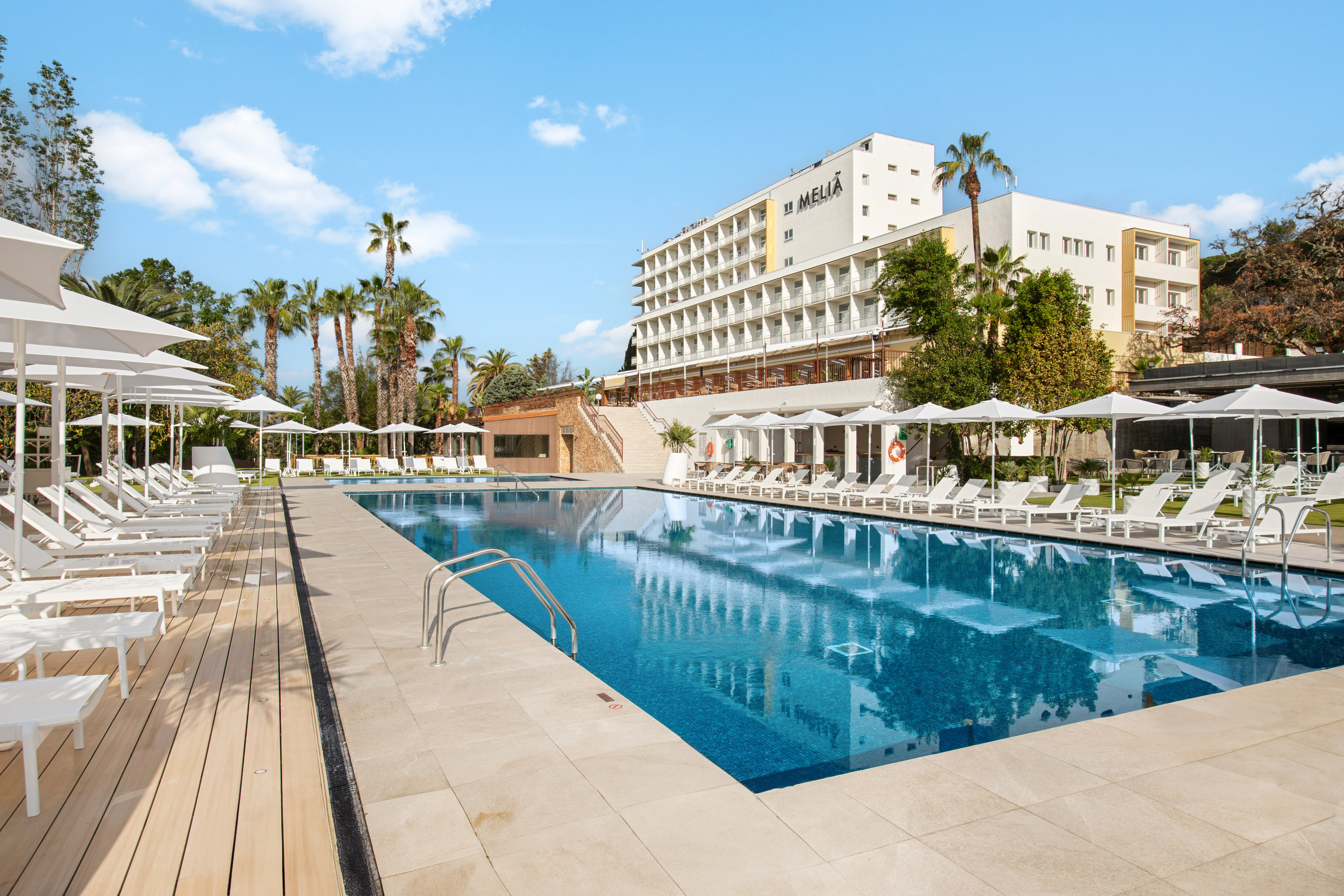 a pool with chairs and umbrellas in front of a building