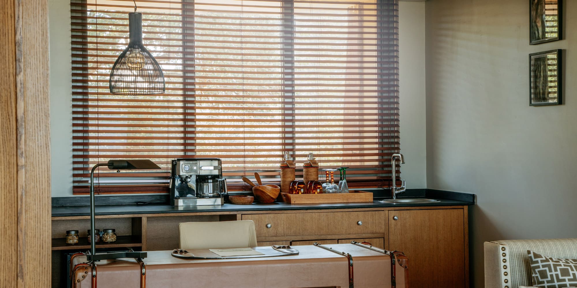 Contemporary hotel room coffee station and desk with wooden blinds.
