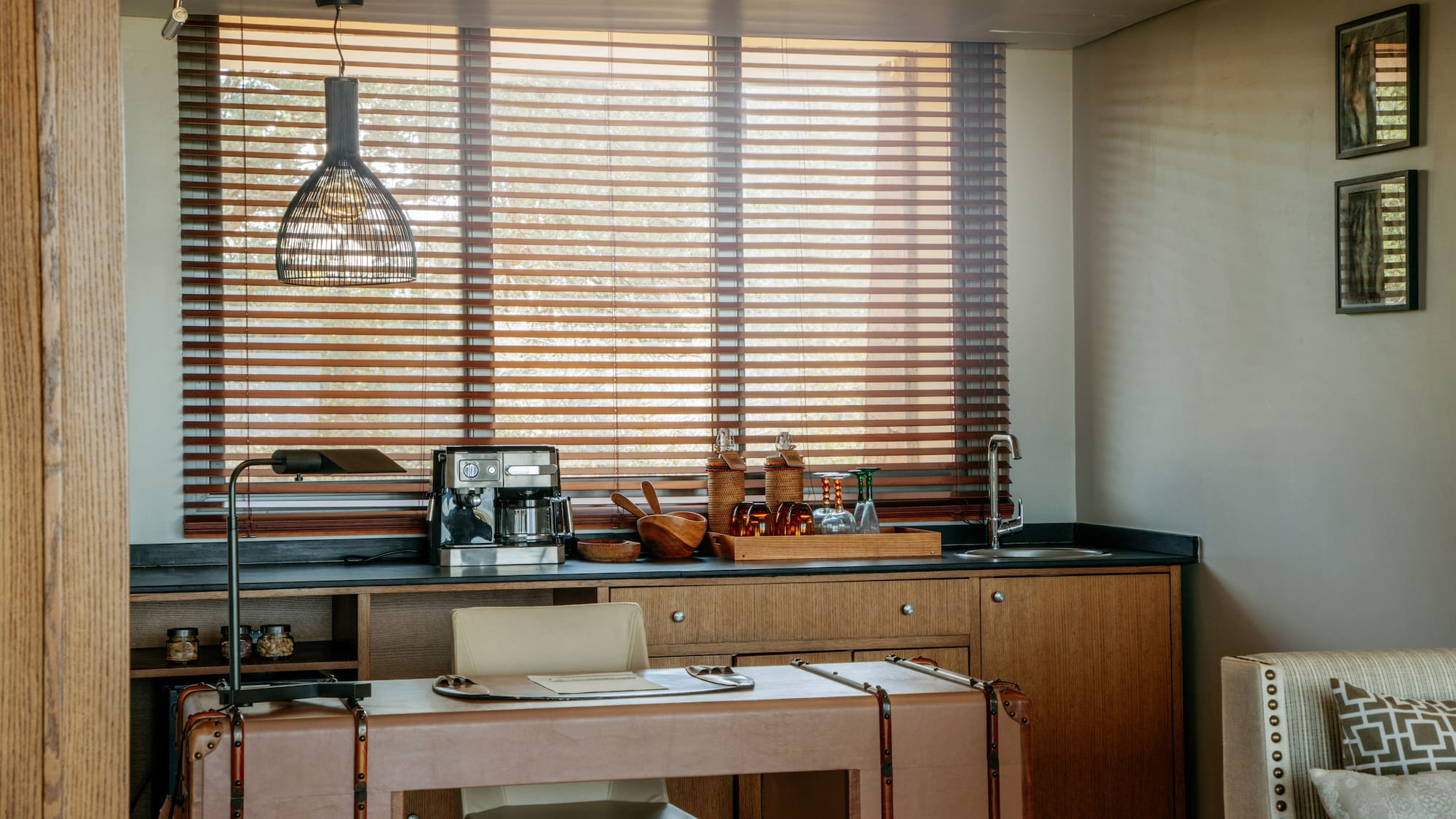 Contemporary hotel room coffee station and desk with wooden blinds.