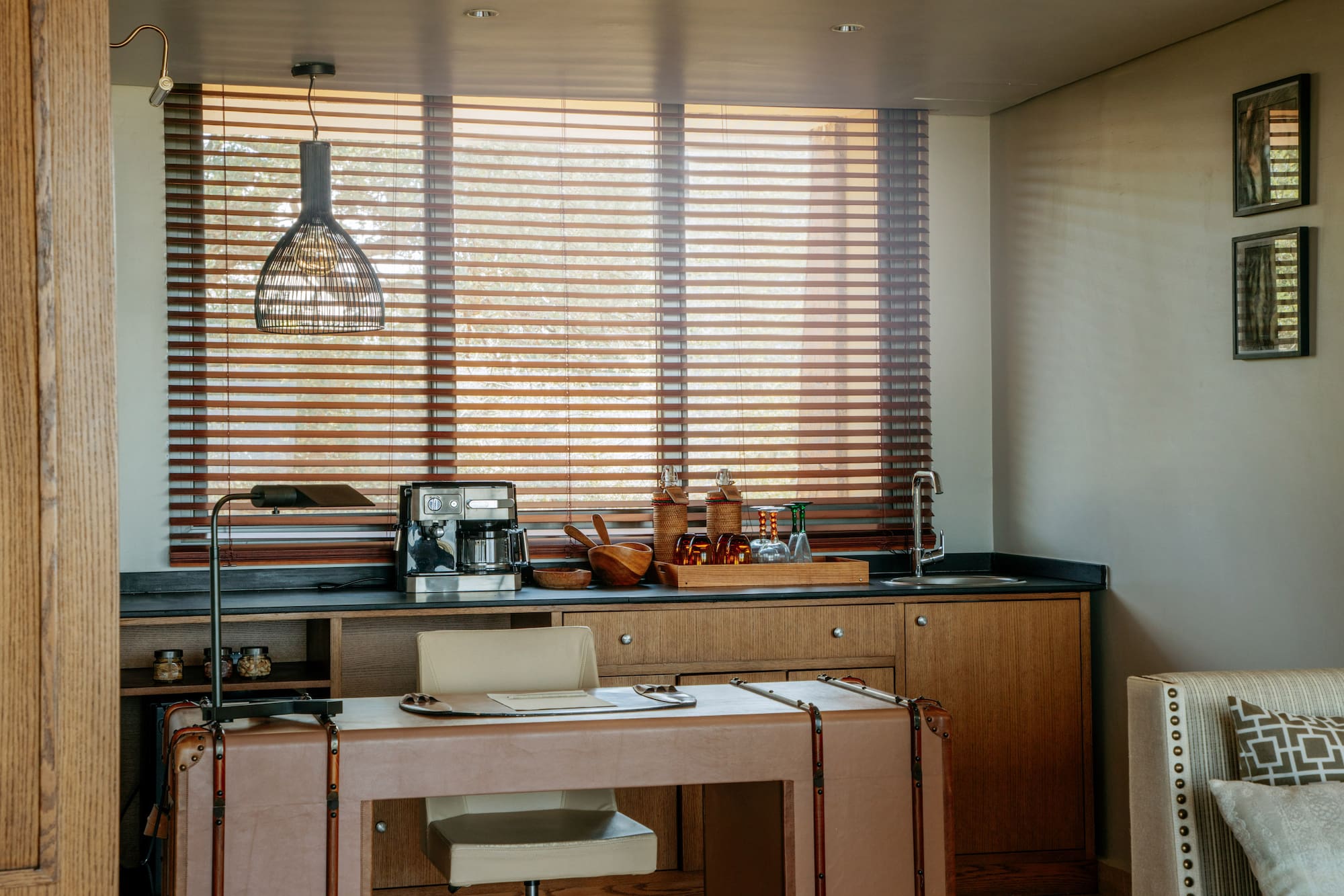 Contemporary hotel room coffee station and desk with wooden blinds.