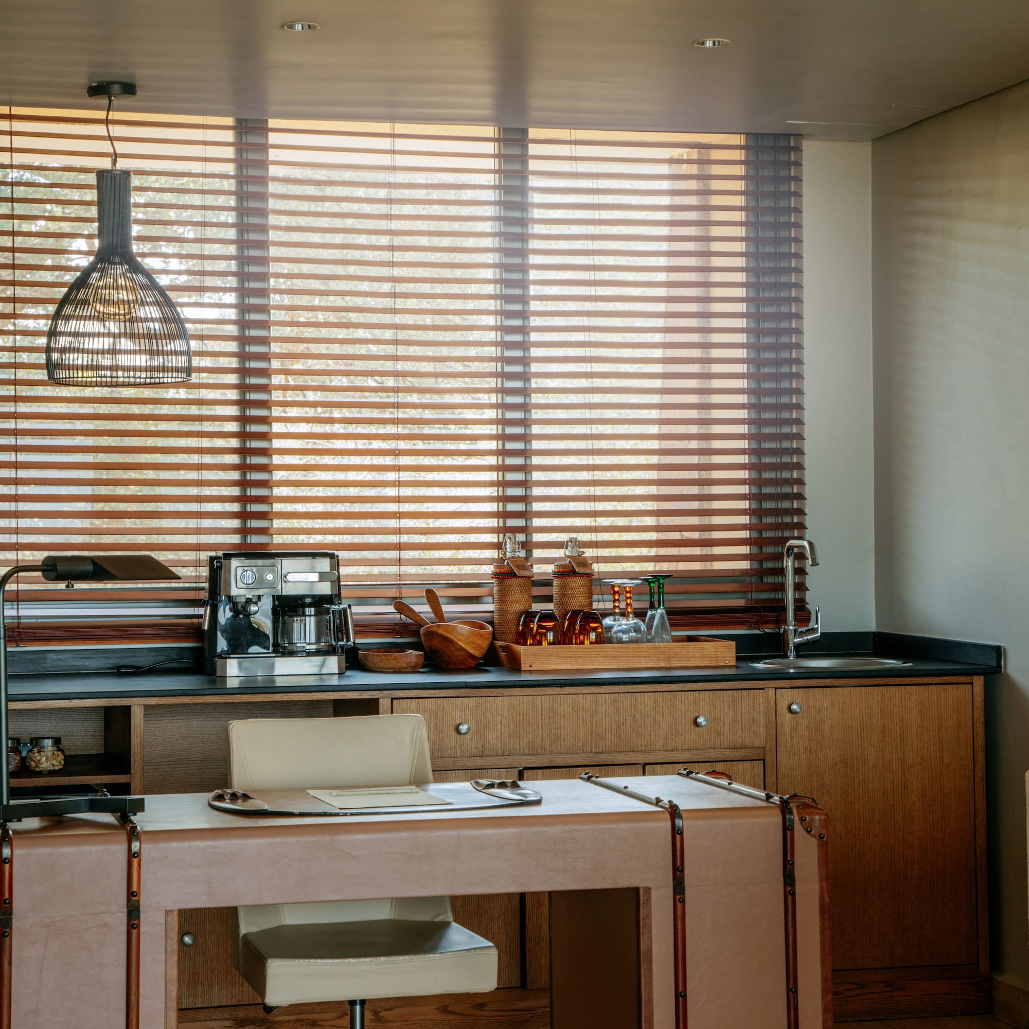 Contemporary hotel room coffee station and desk with wooden blinds.