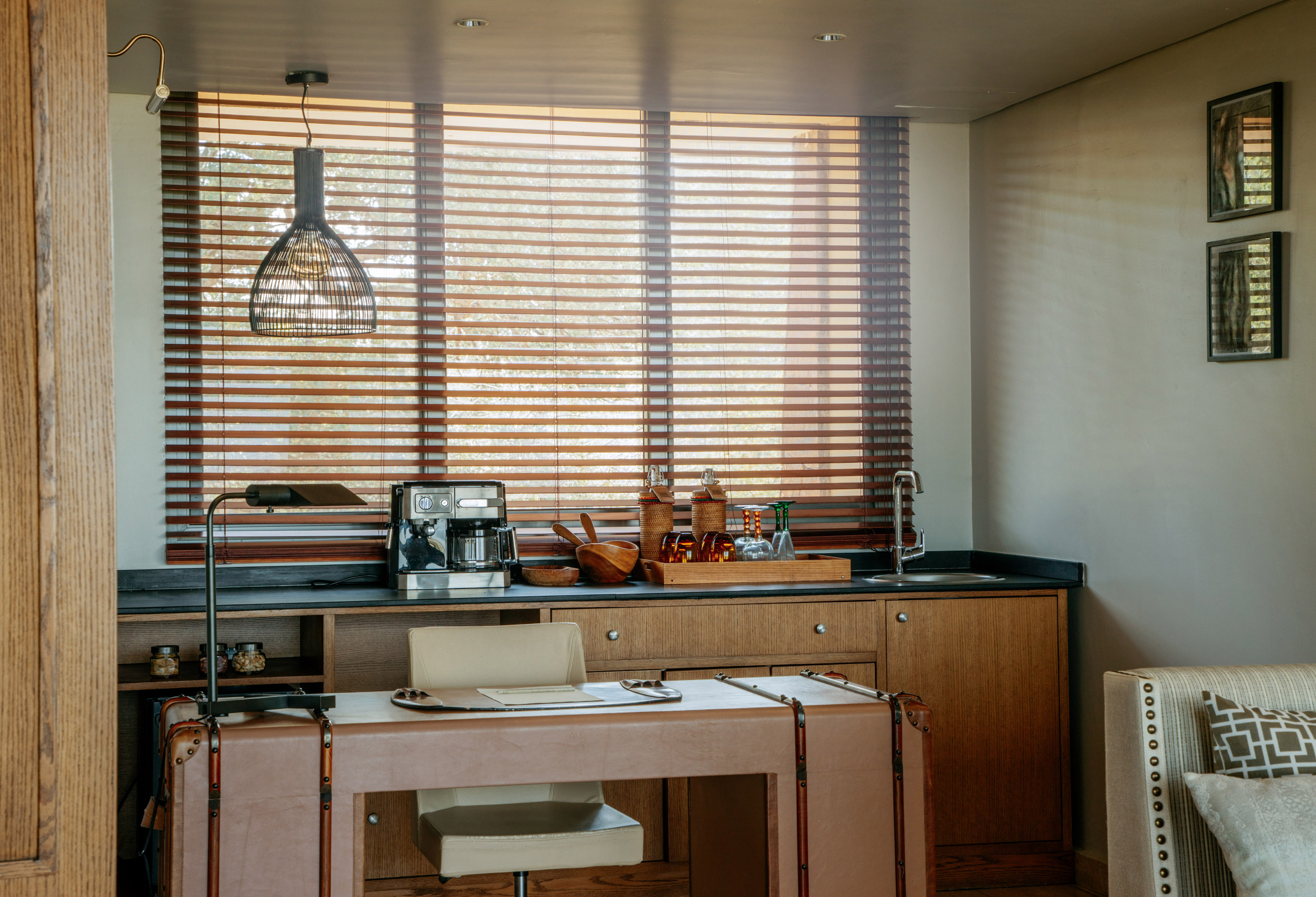 Contemporary hotel room coffee station and desk with wooden blinds.