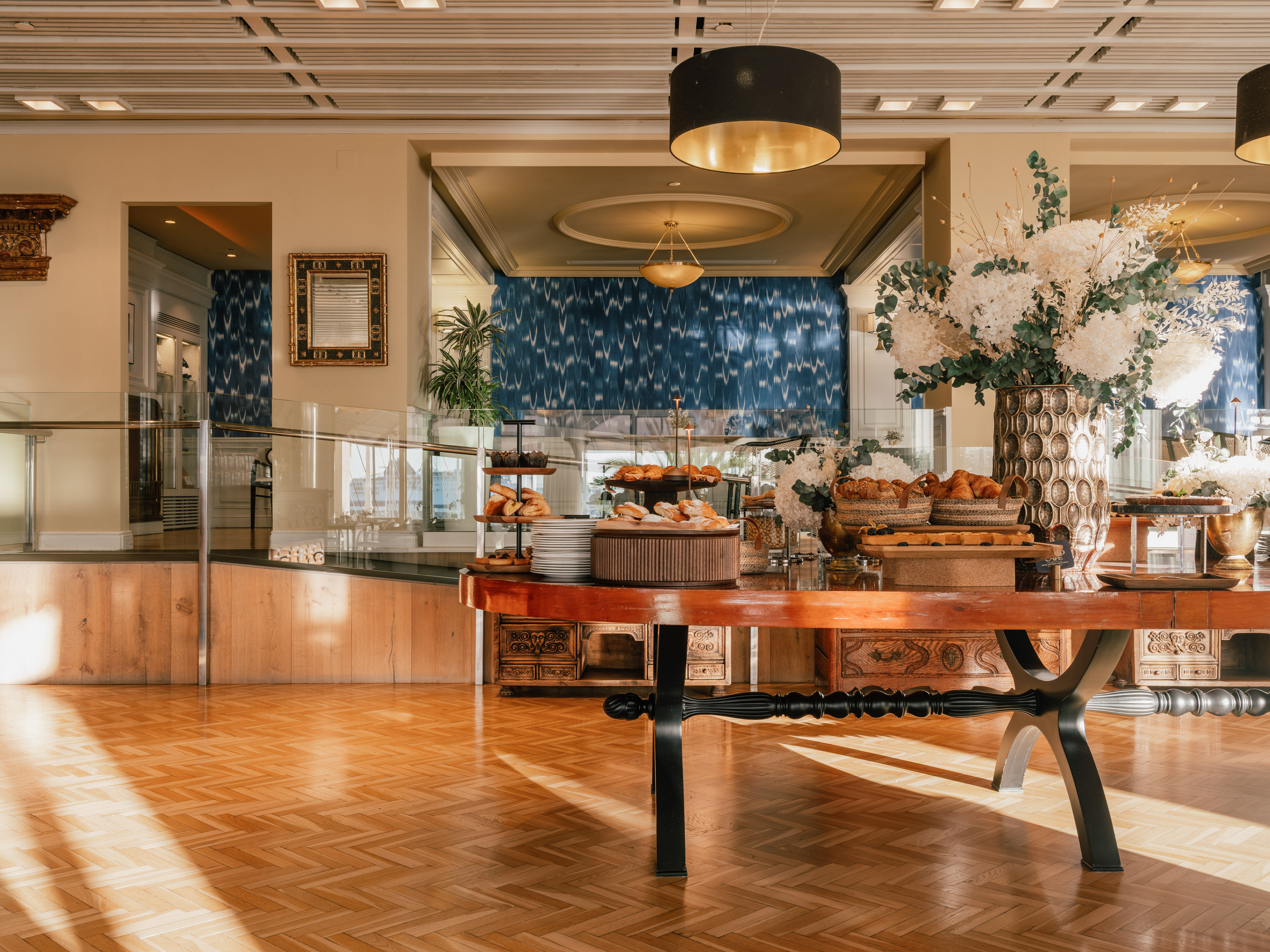 Luxurious hotel breakfast buffet with pastries, croissants, and elegant floral decor.