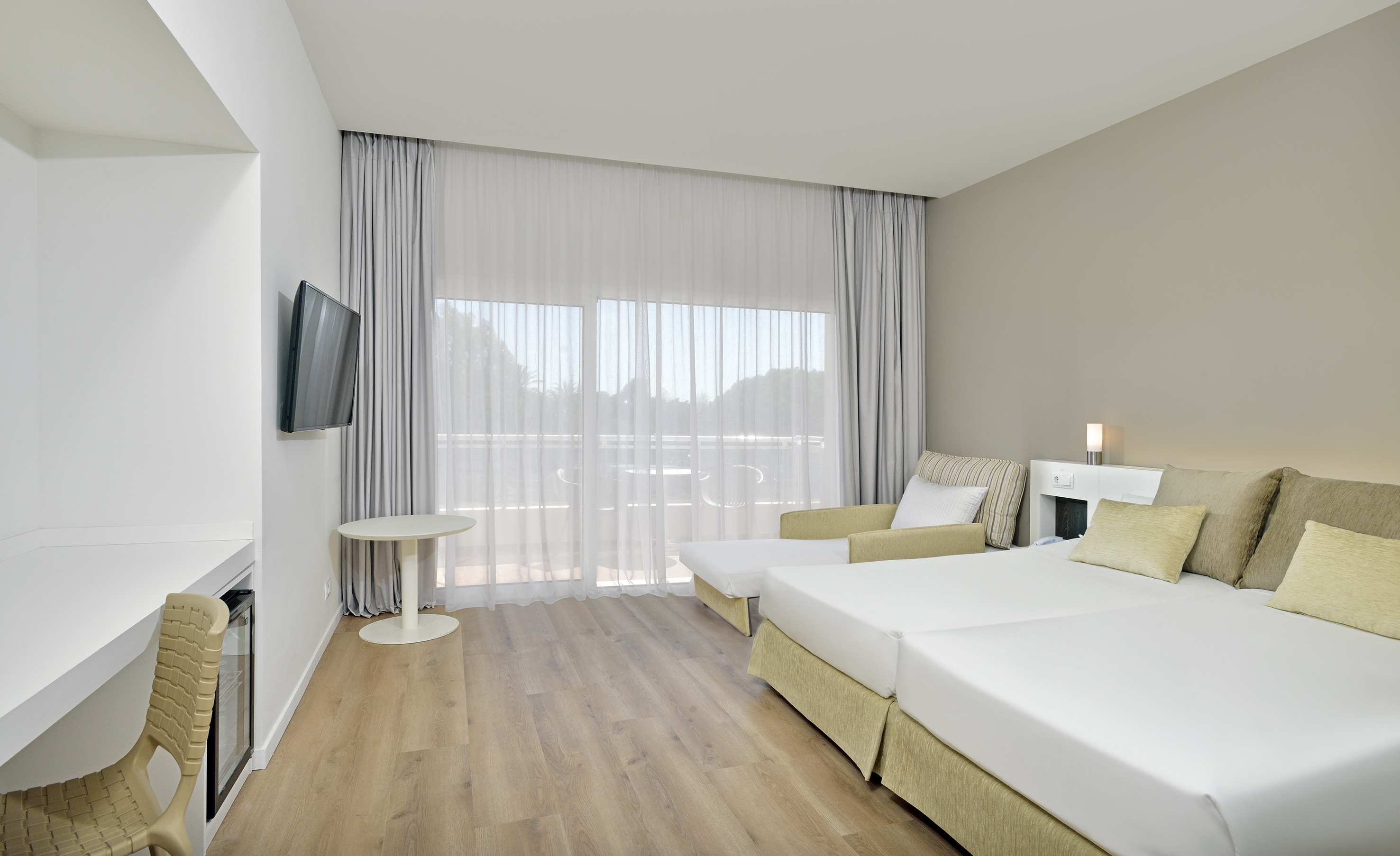 Bright modern hotel room with twin beds, balcony, TV, and minimalist decor.