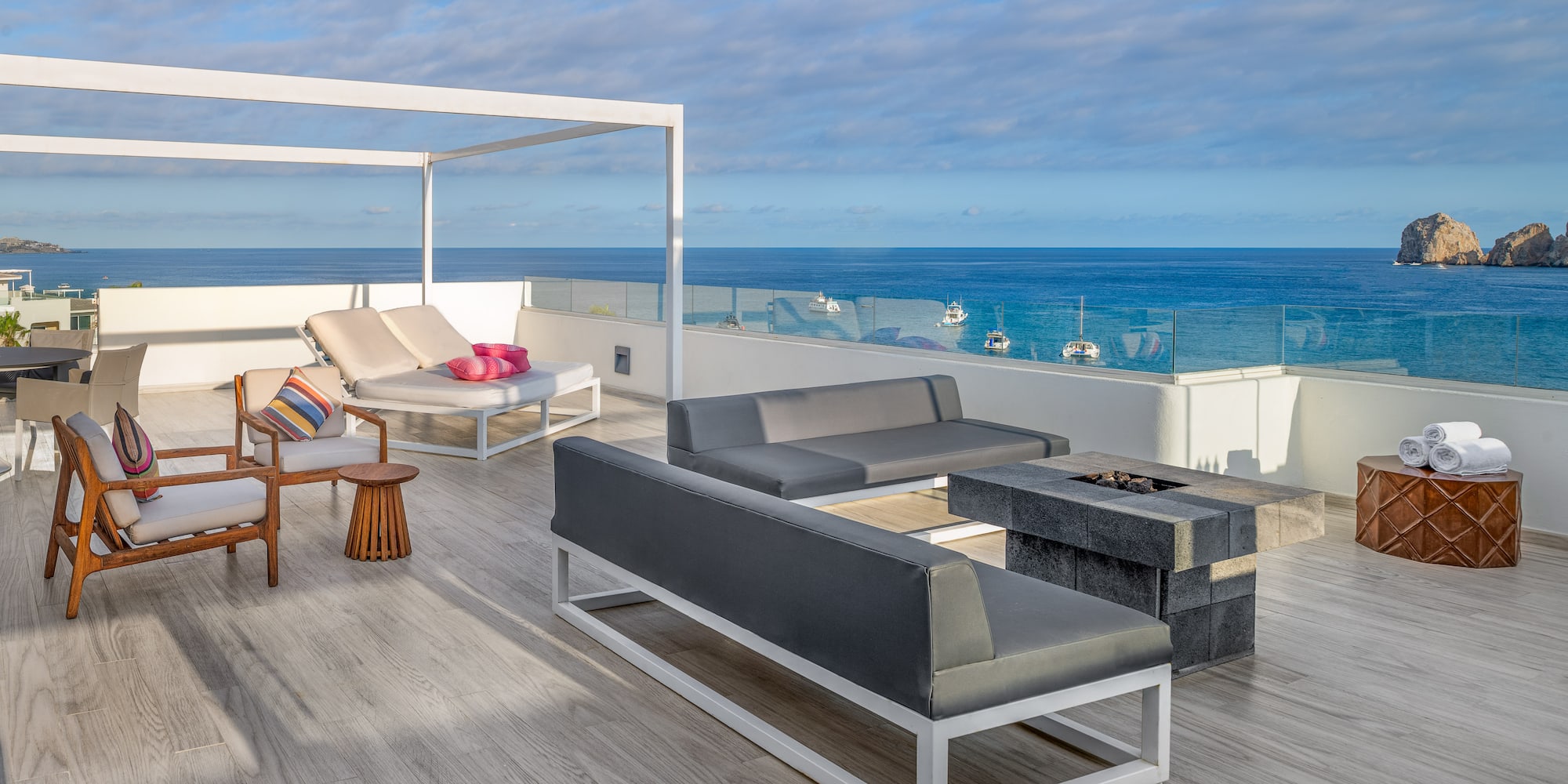 a deck with a patio furniture and a fire pit overlooking the ocean