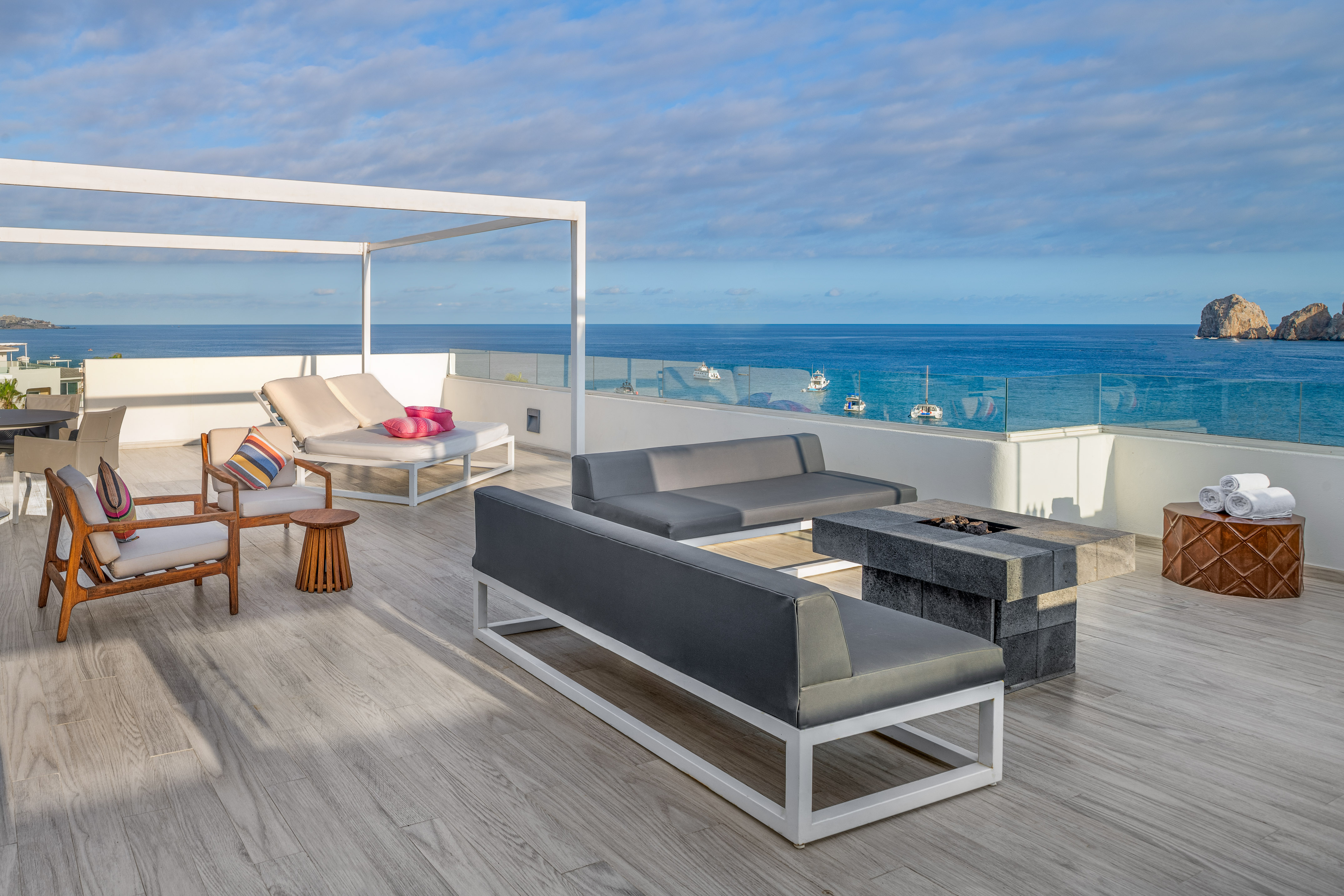 a deck with a patio furniture and a fire pit overlooking the ocean