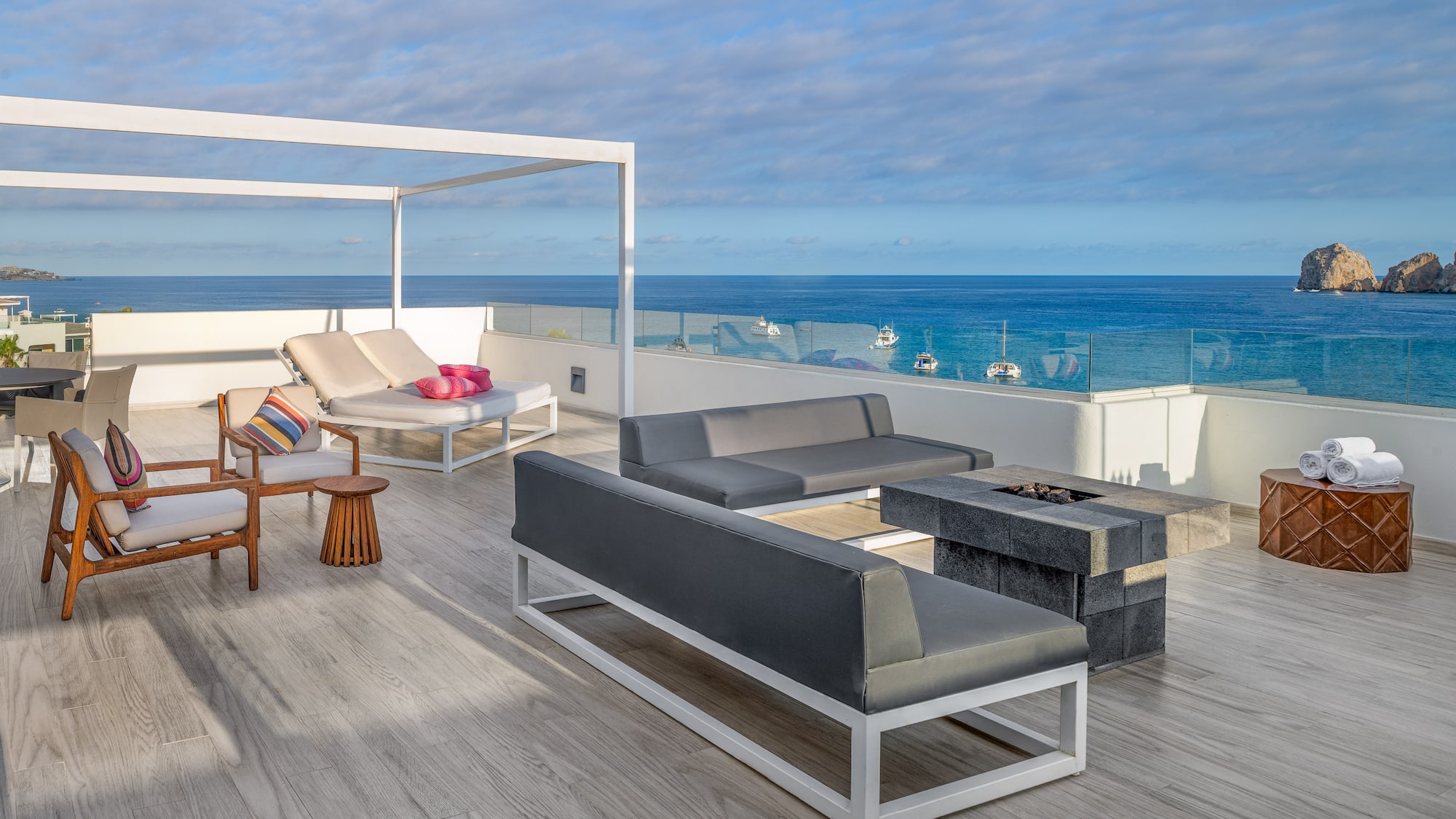 a deck with a patio furniture and a fire pit overlooking the ocean