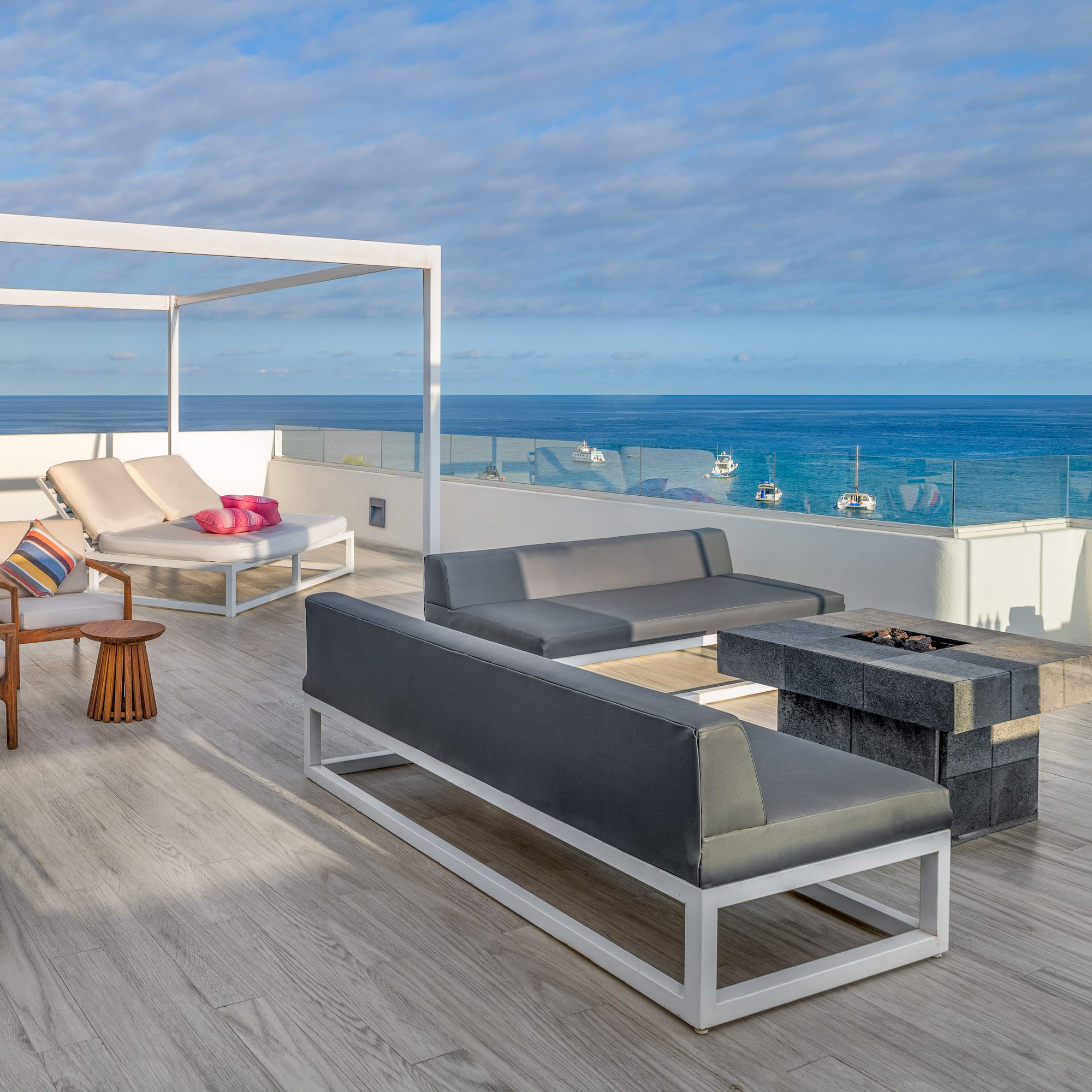 a deck with a patio furniture and a fire pit overlooking the ocean