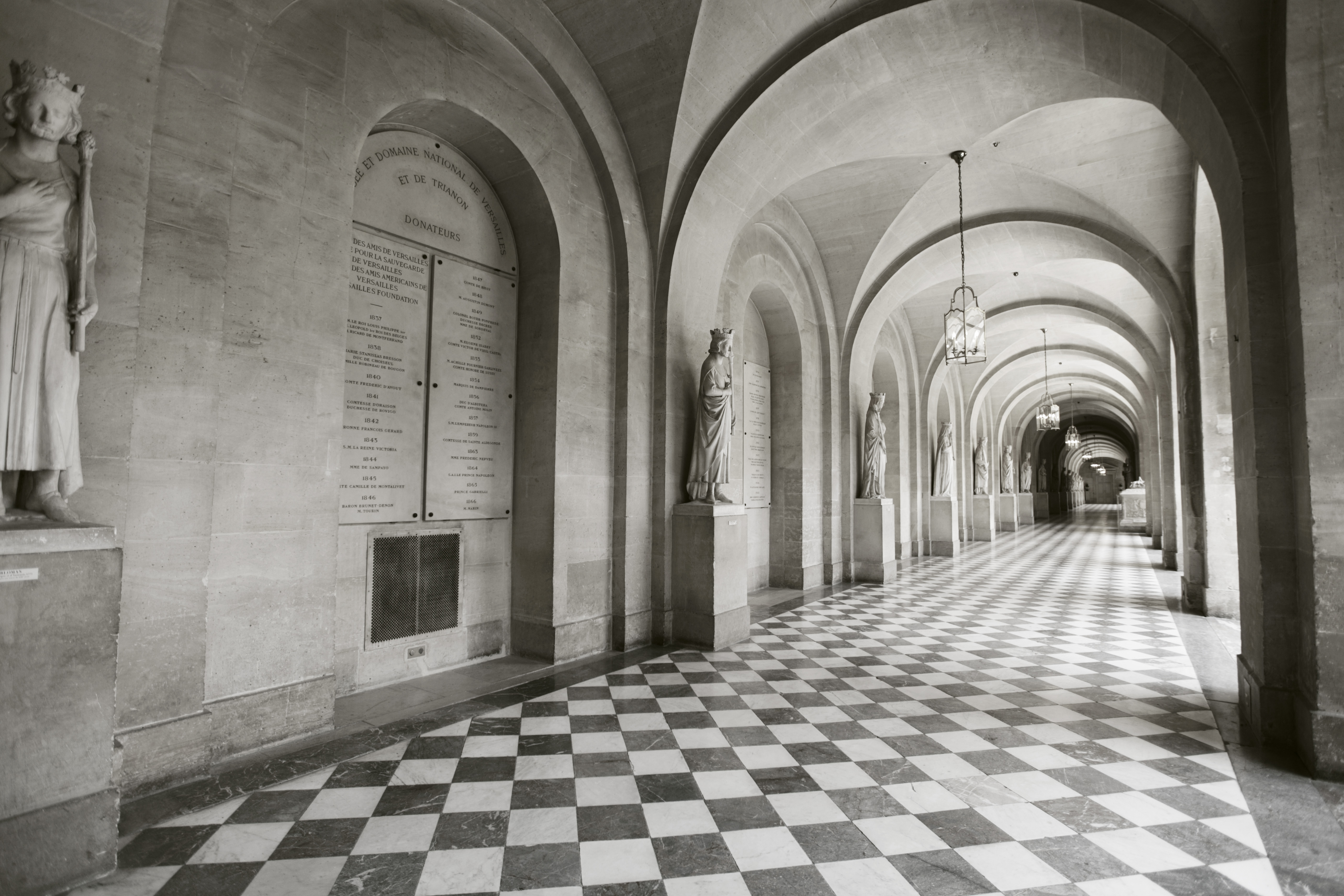 a long hallway with stone arches and statues