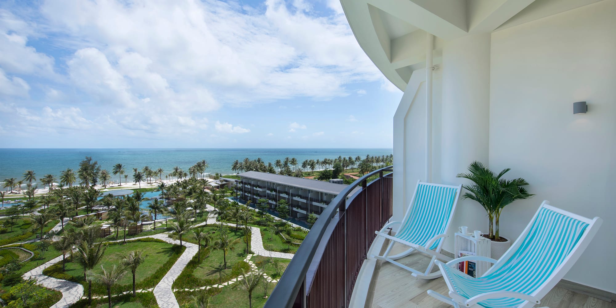 a deck with chairs and palm trees and a beach