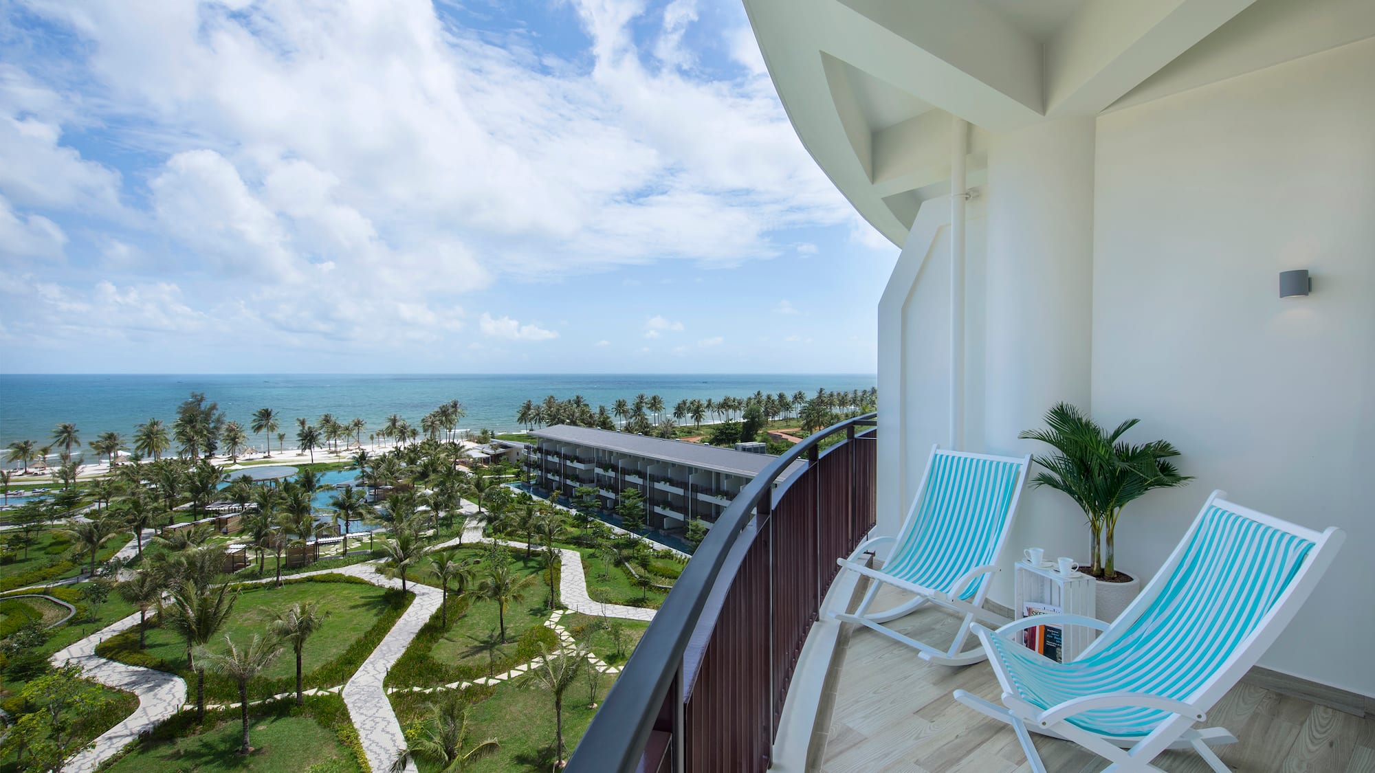 a deck with chairs and palm trees and a beach