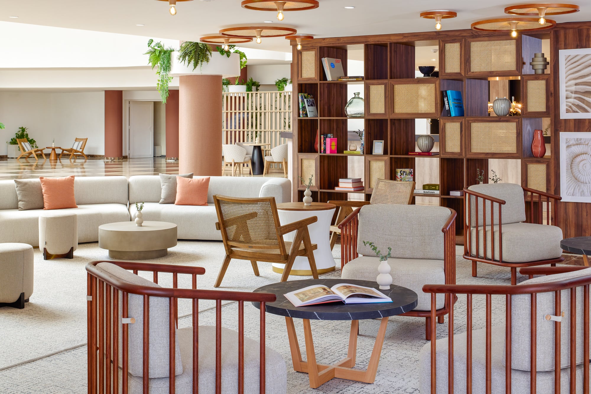 Modern hotel lobby lounge with comfortable seating, wood rattan shelves, and warm tones.