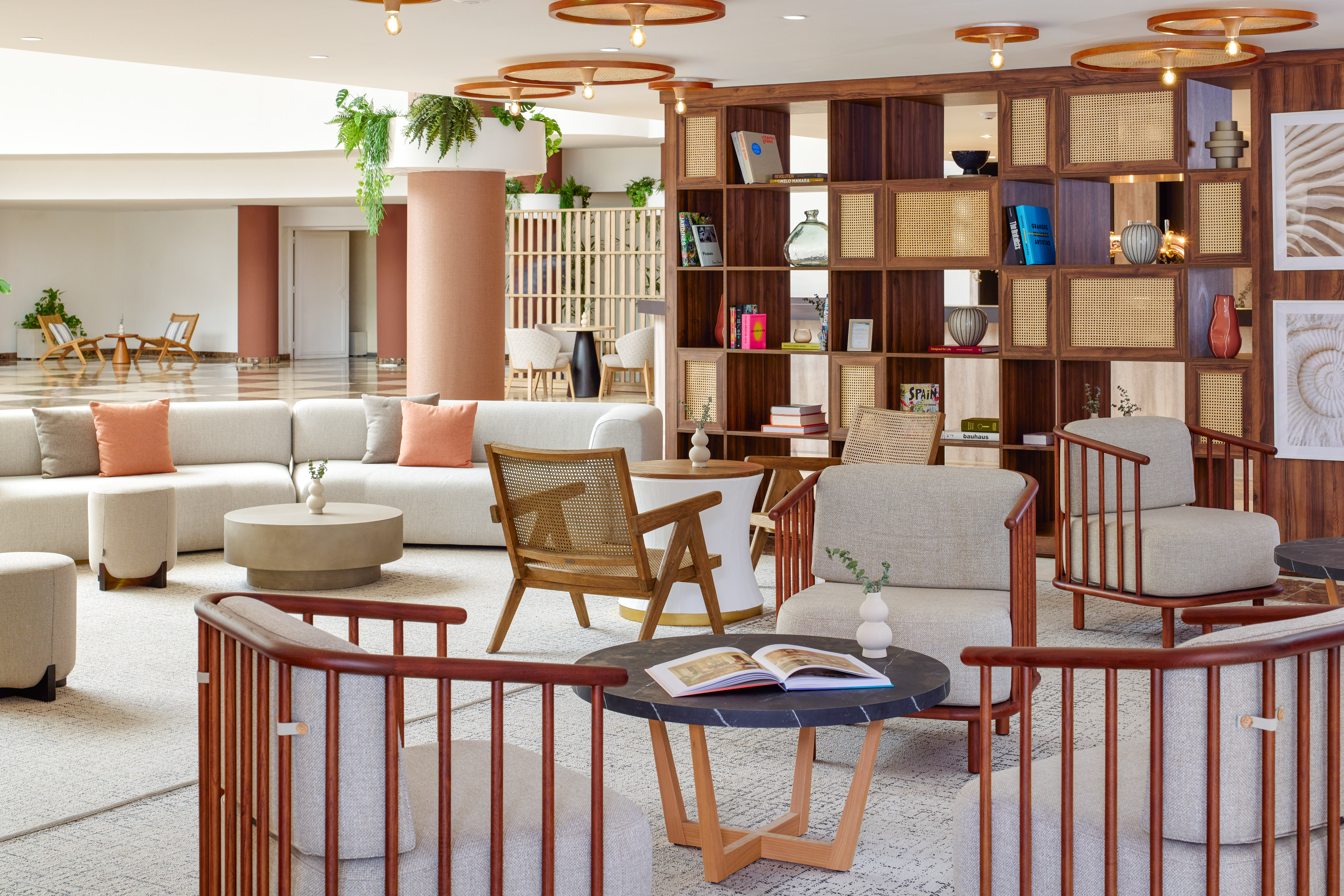 Modern hotel lobby lounge with comfortable seating, wood rattan shelves, and warm tones.