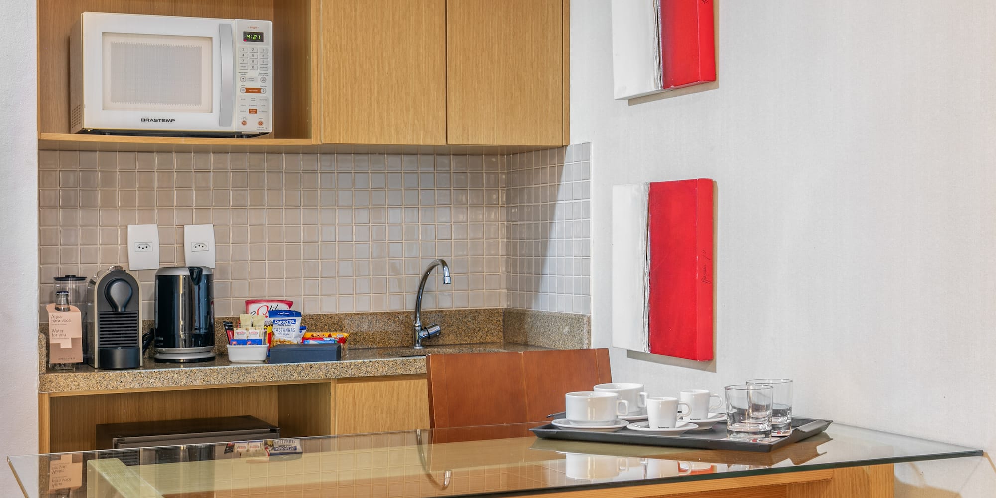a kitchen with a microwave and coffee cups