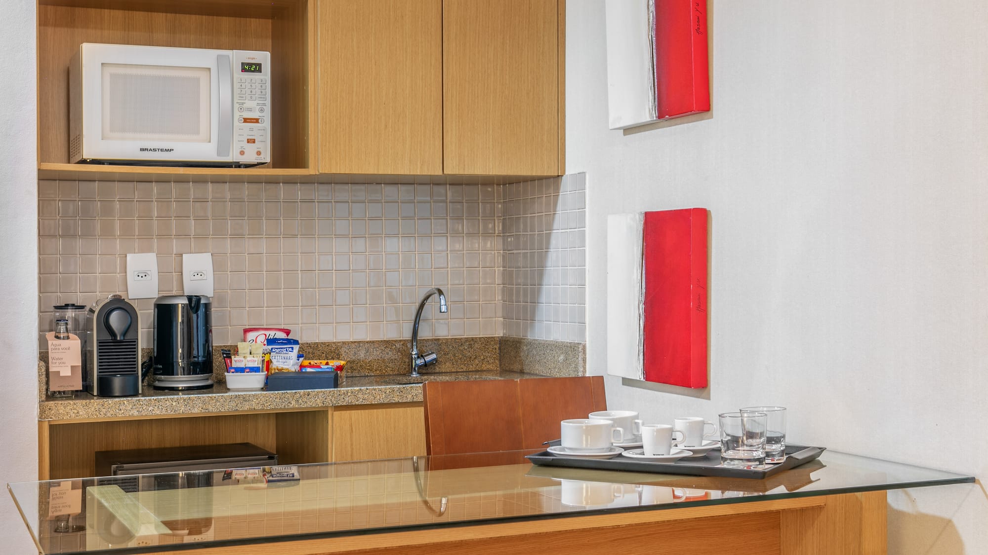 a kitchen with a microwave and coffee cups