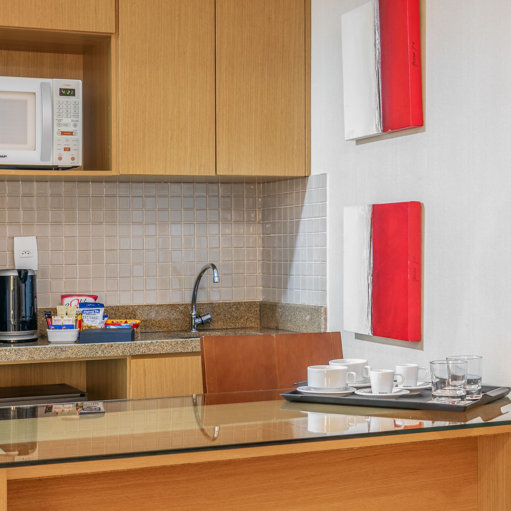 a kitchen with a microwave and coffee cups