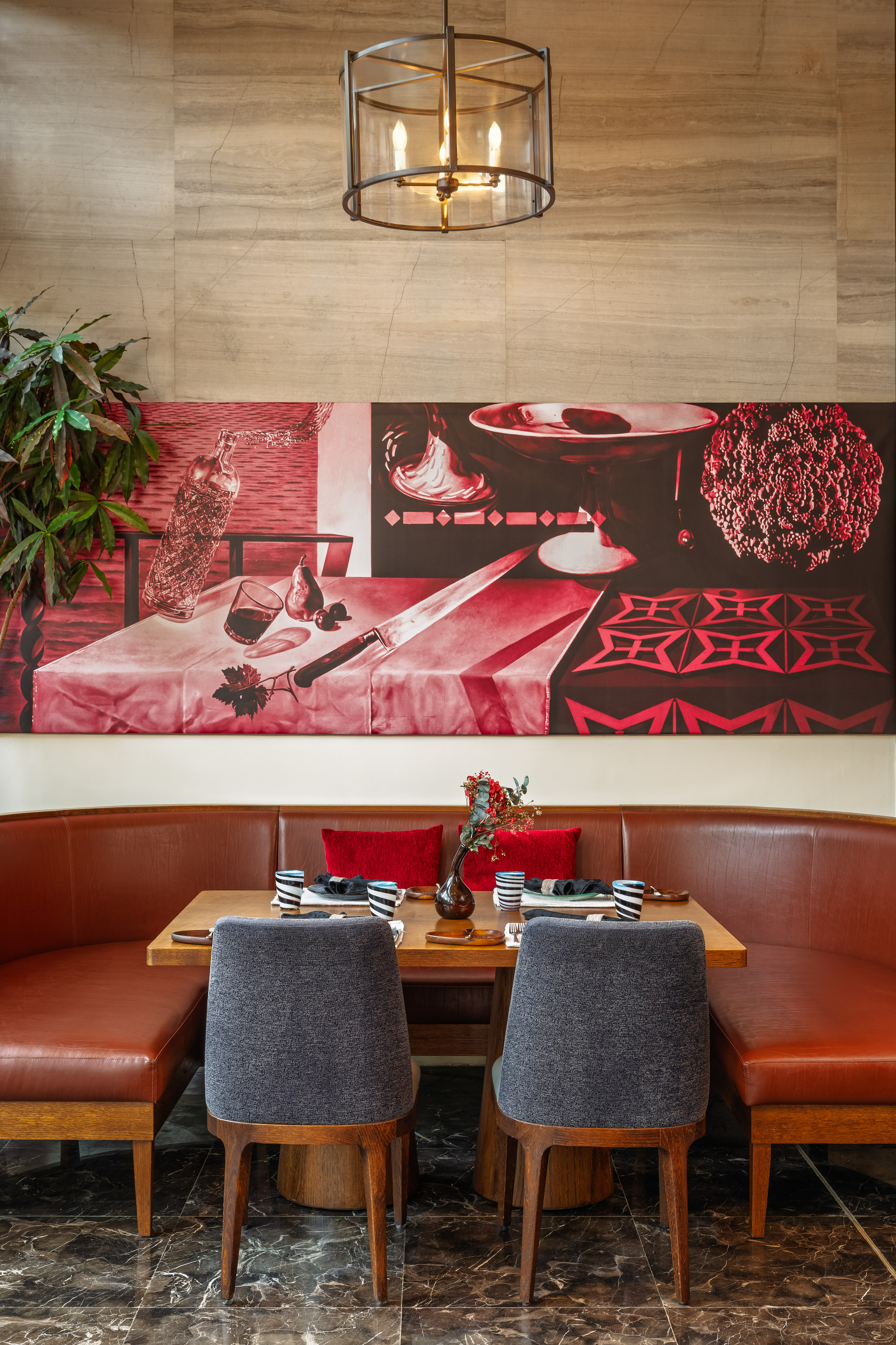 Restaurant booth with brown leather, wooden table, and red still-life art.