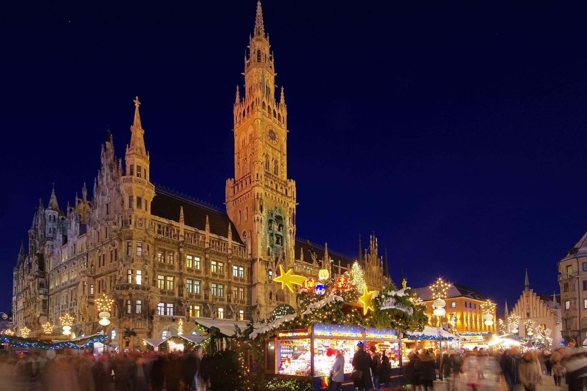 Mercado navideño en Marienplatz, Múnich, con el Nuevo Ayuntamiento gótico iluminado.