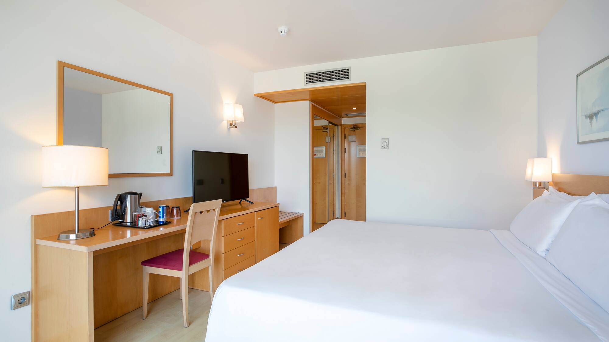 a room with a bed and a desk and a mirror