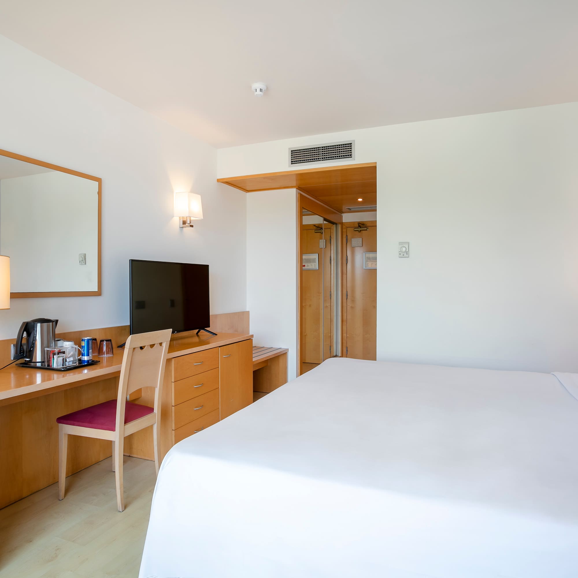 a room with a bed and a desk and a mirror