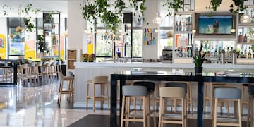a room with a bar and a counter with chairs and plants from the ceiling