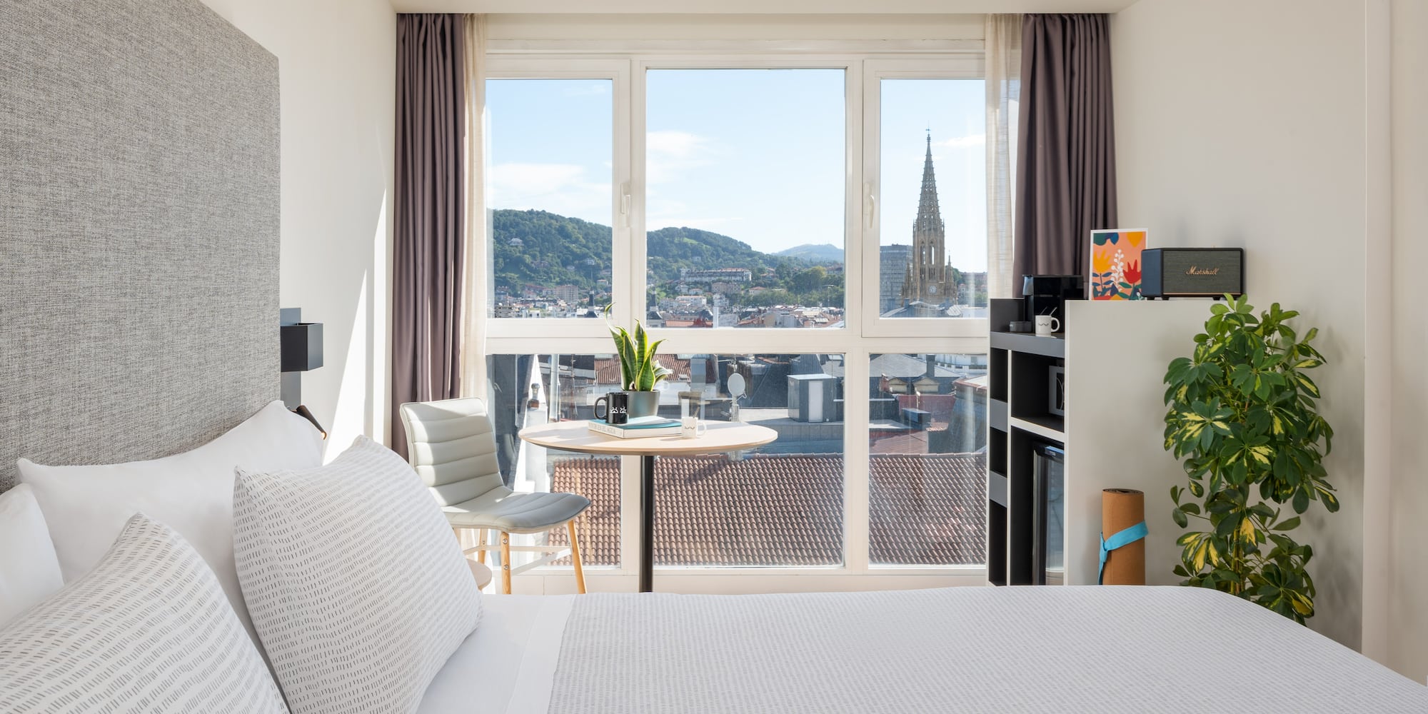 a bedroom with a large window and a table and a chair