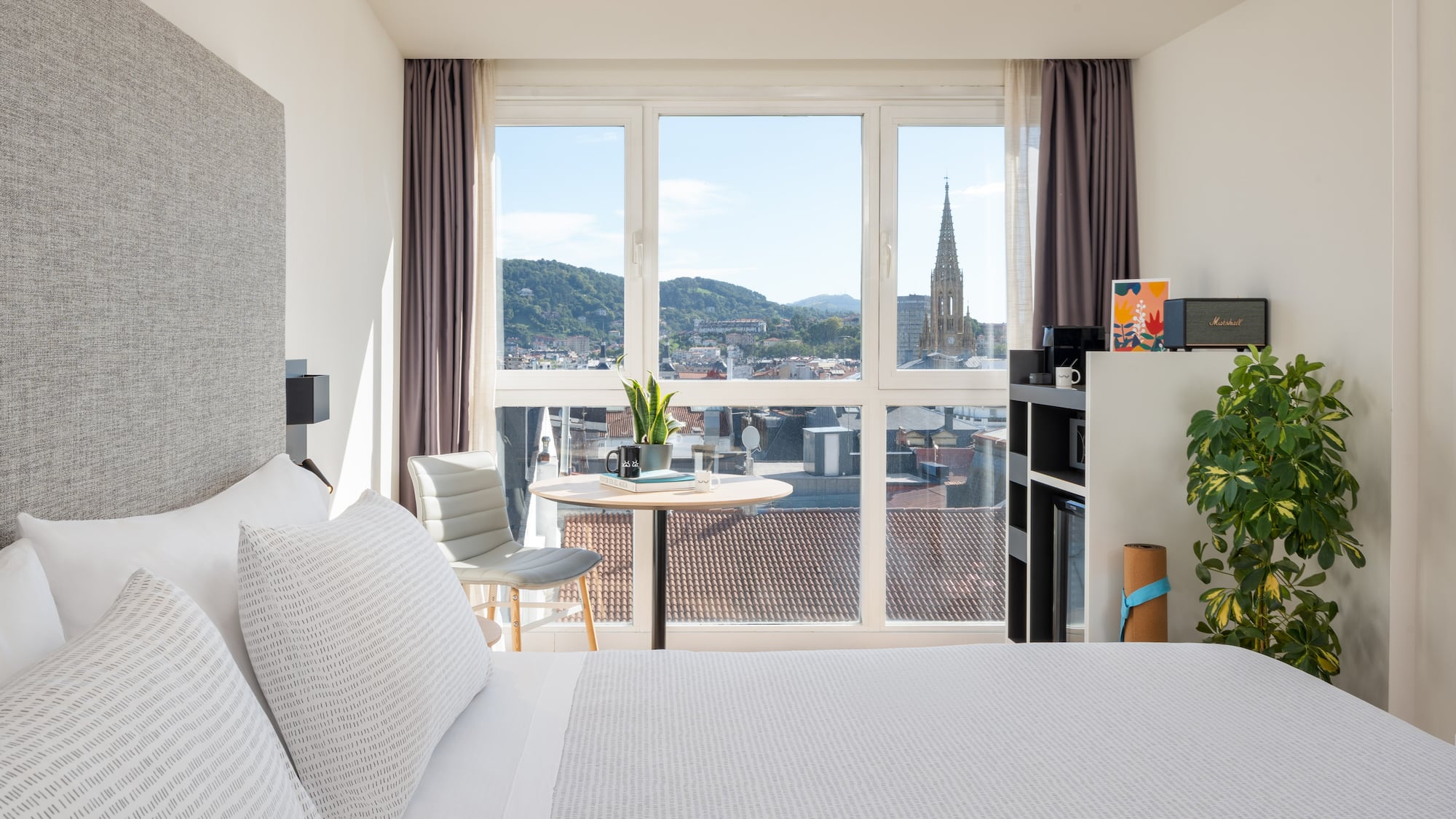 a bedroom with a large window and a table and a chair