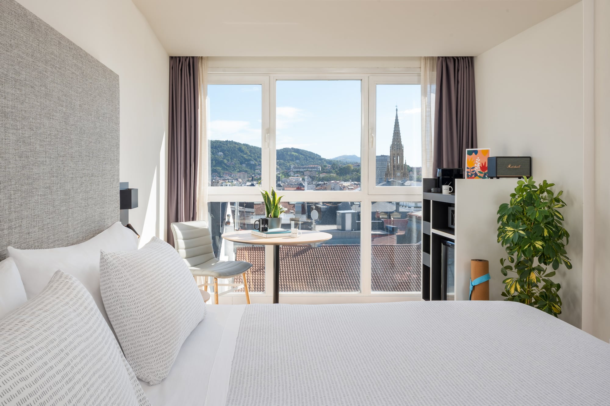 a bedroom with a large window and a table and a chair