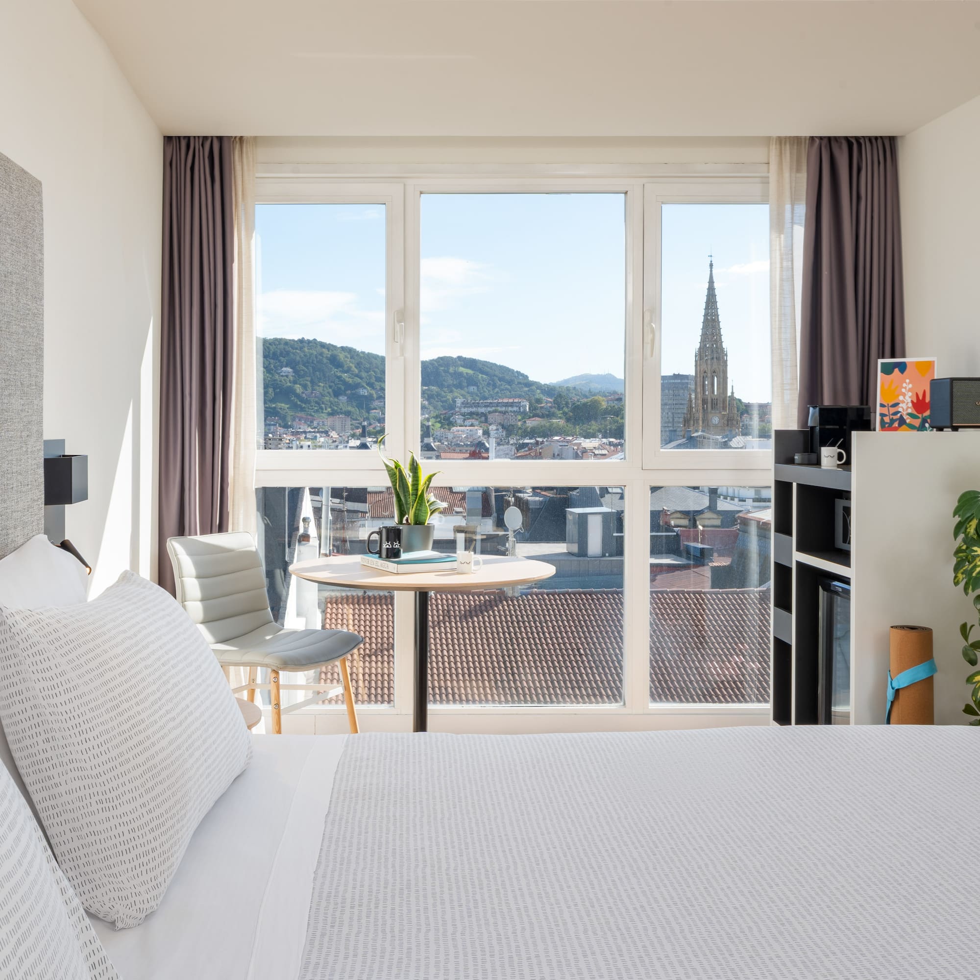 a bedroom with a large window and a table and a chair