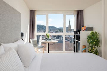 a bedroom with a large window and a table and a chair