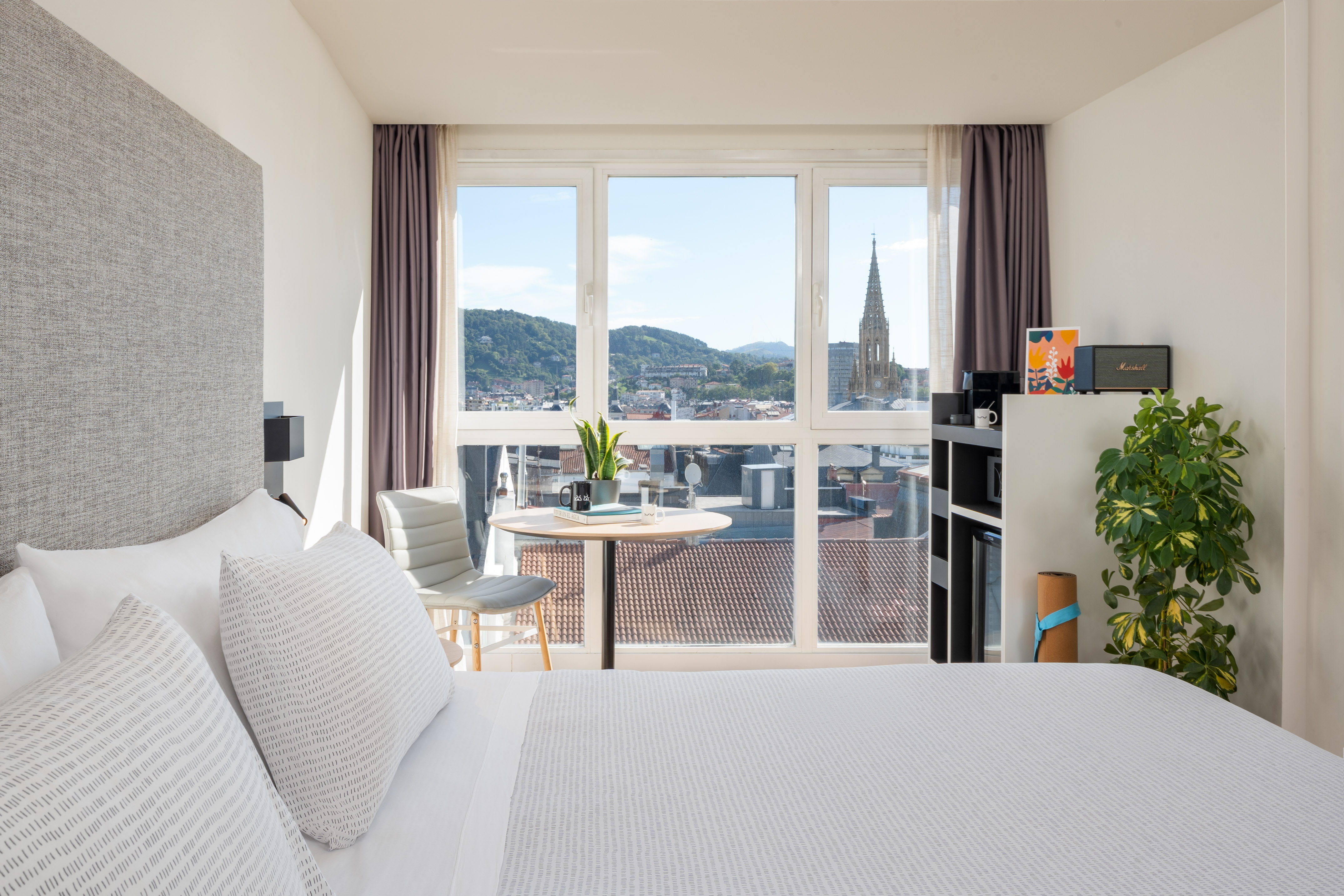 a bedroom with a large window and a table and a chair