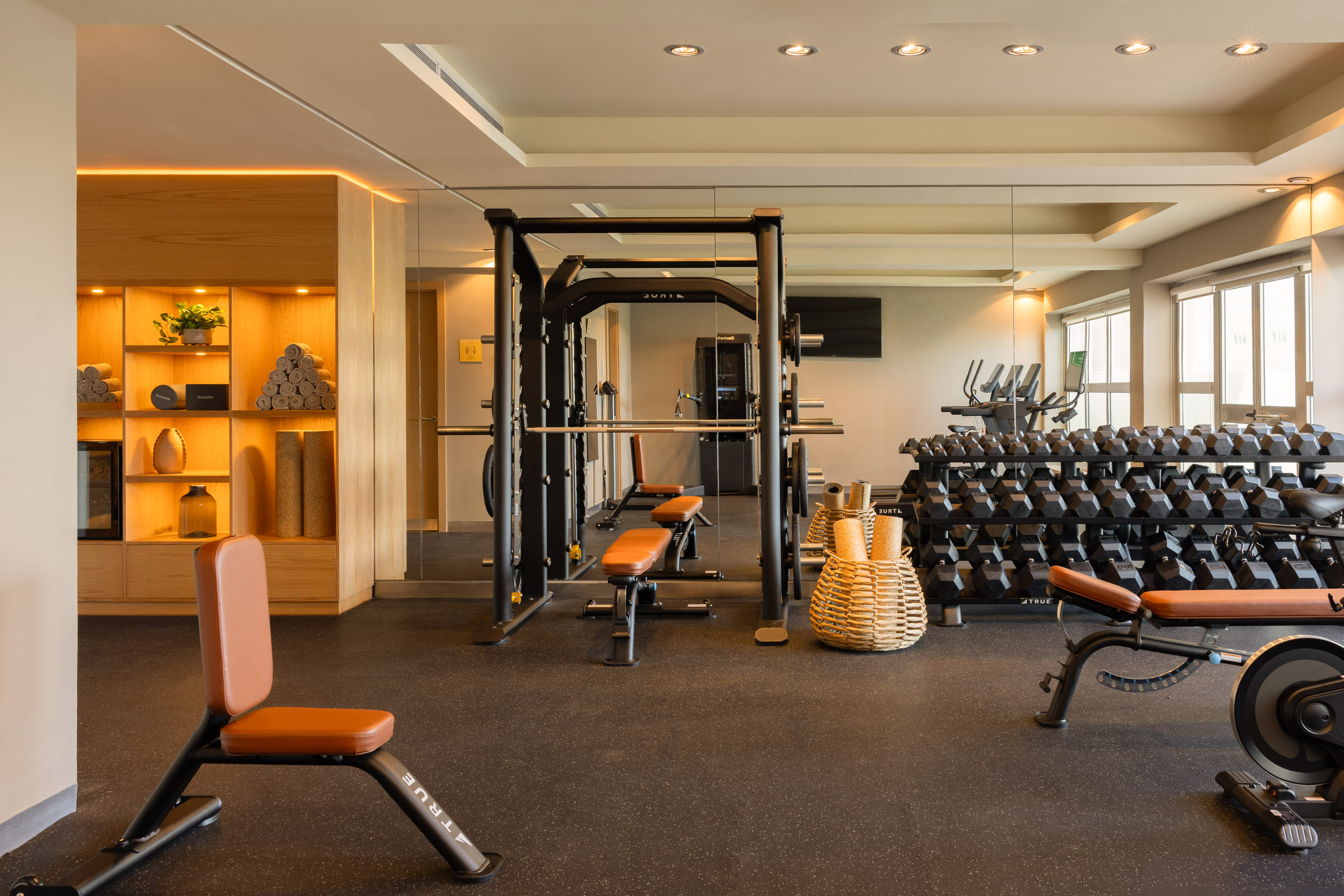 Well-lit modern gym with dumbbells, squat rack, and fitness benches.