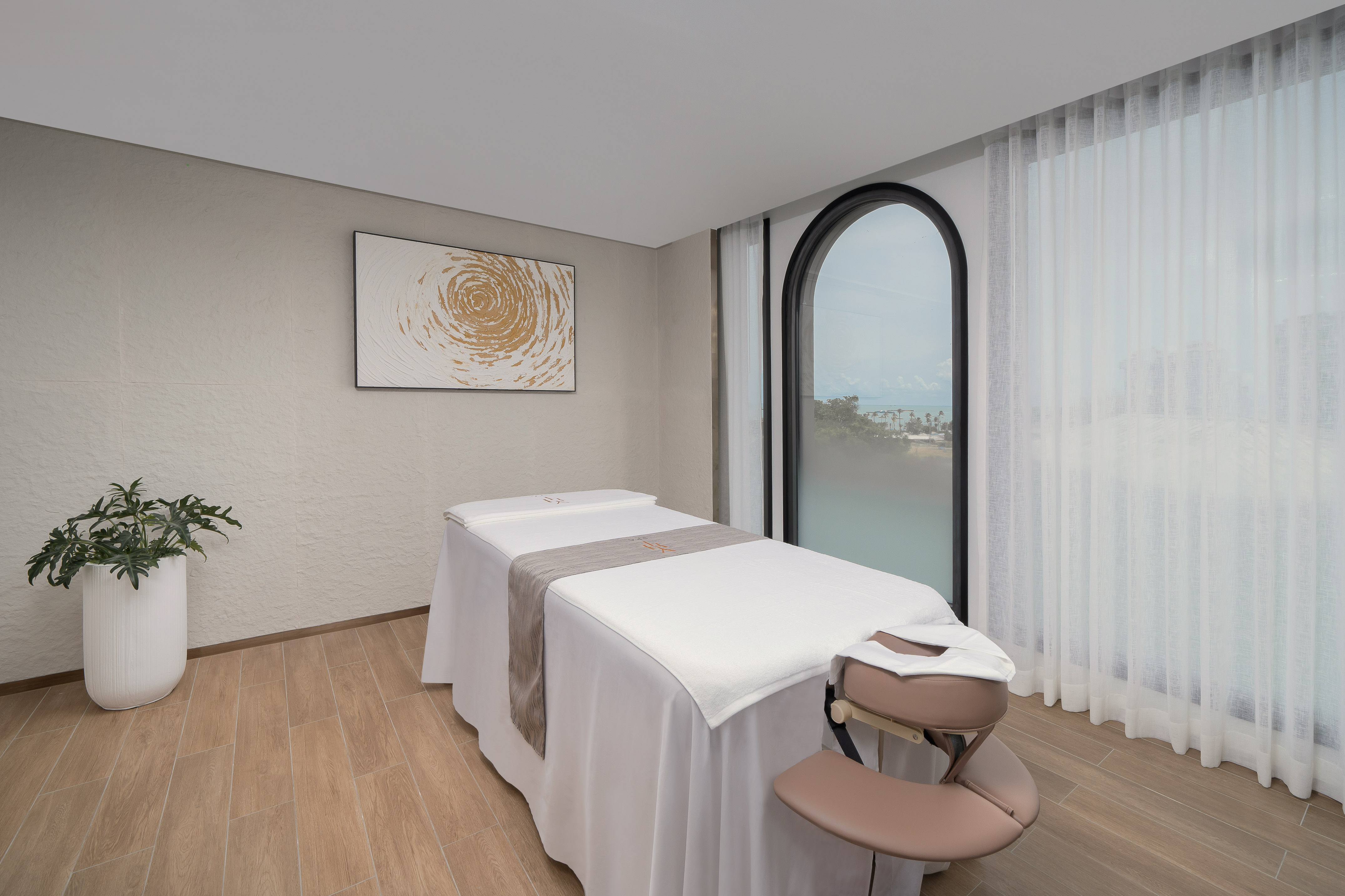 Luxury spa room with massage bed, modern art, and ocean view window. - YHI Spa - Meliá Pattaya Hotel, Pattaya