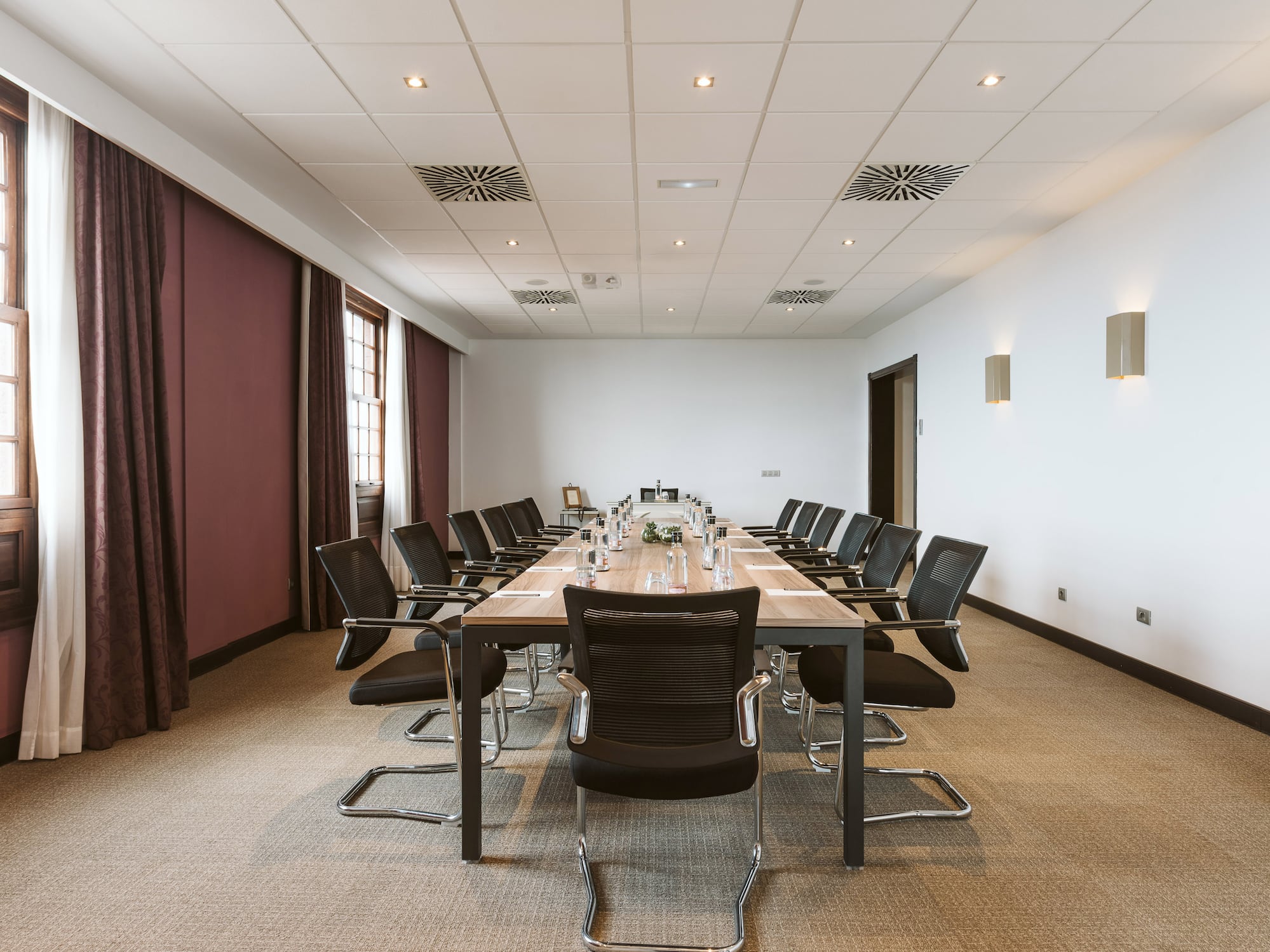 Professional meeting room with long table, black chairs, and large windows.