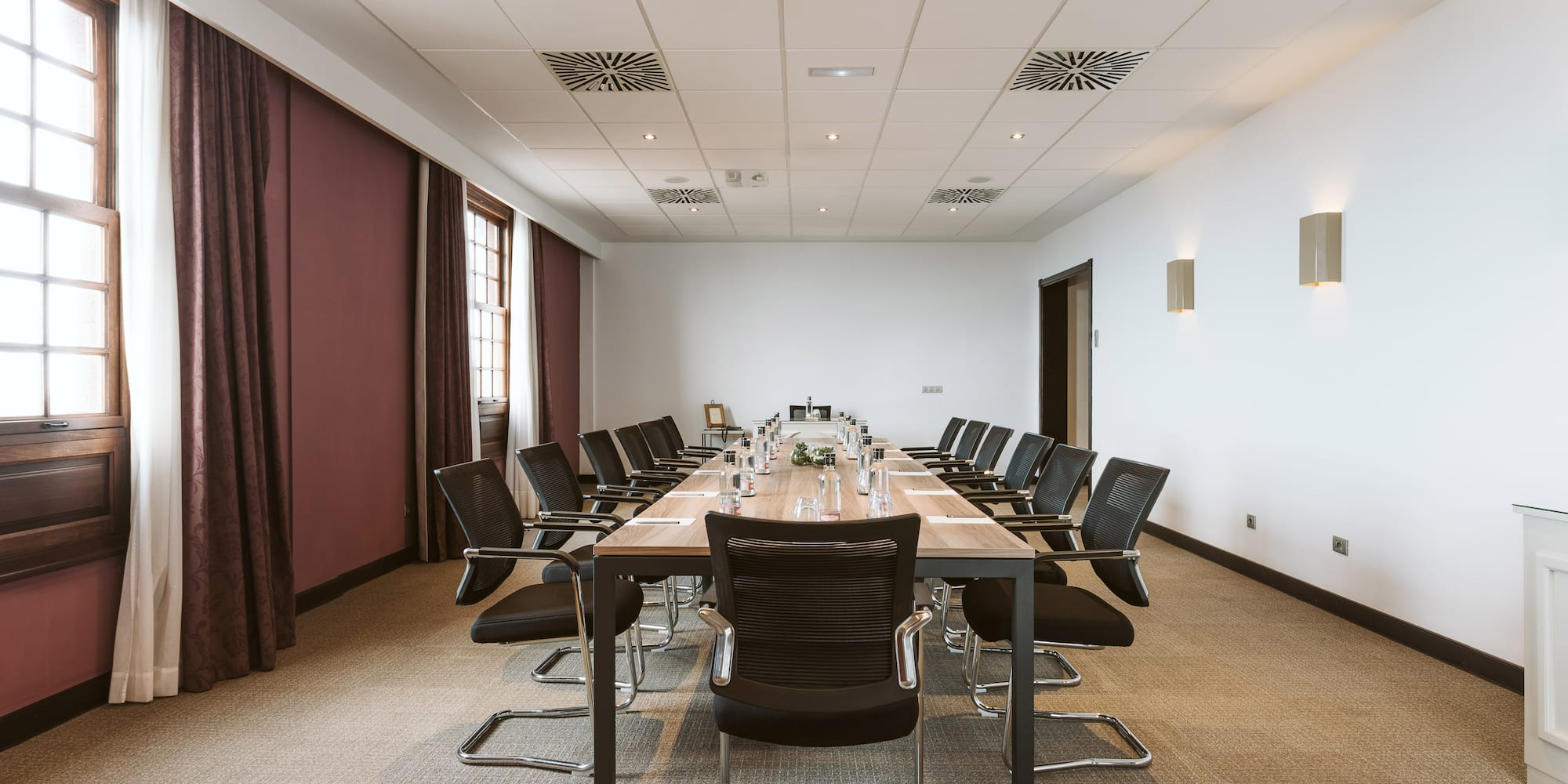 Spacious corporate meeting room with large table and black chairs.