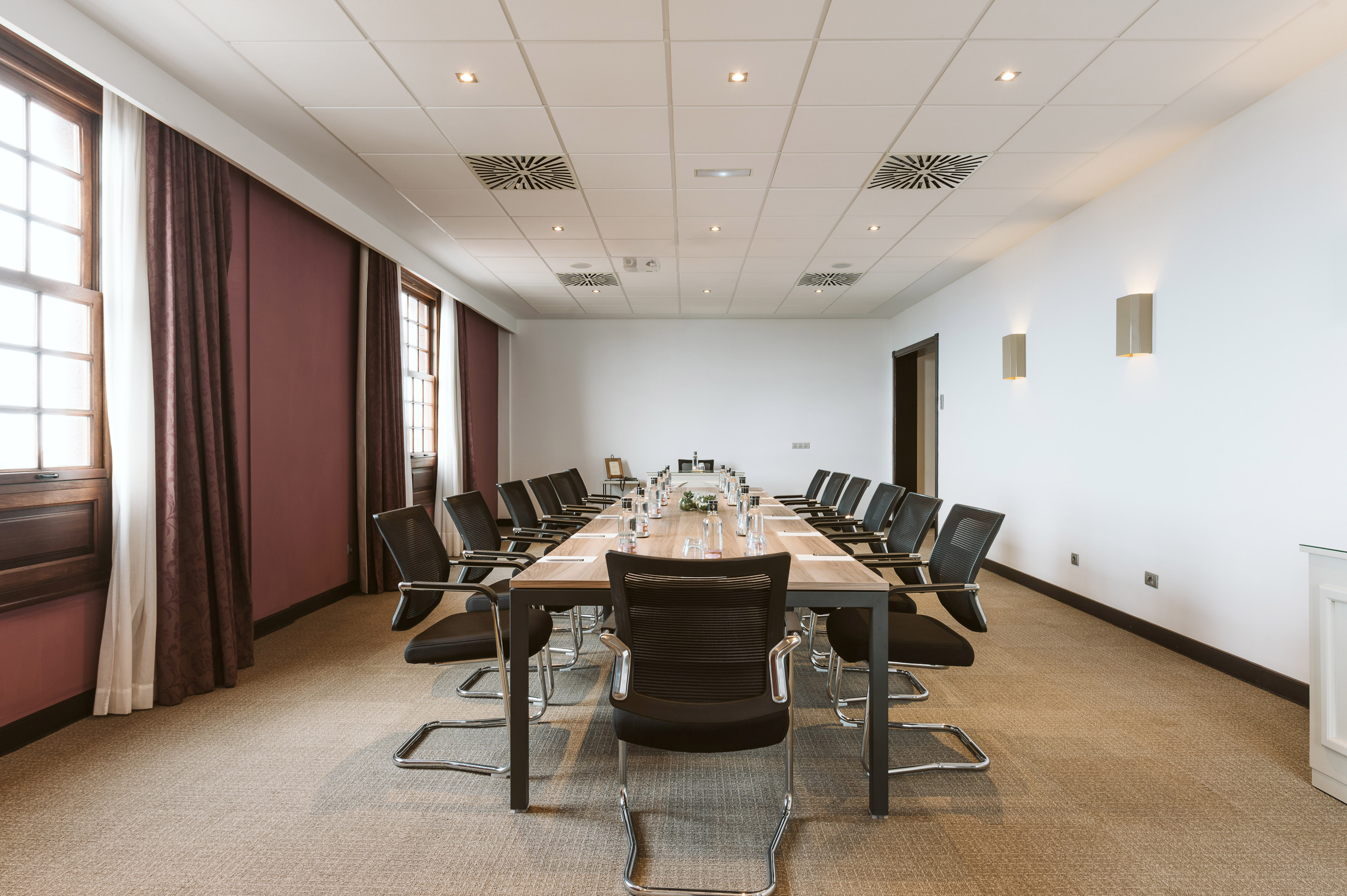 Professional meeting room with long table, black chairs, and large windows.